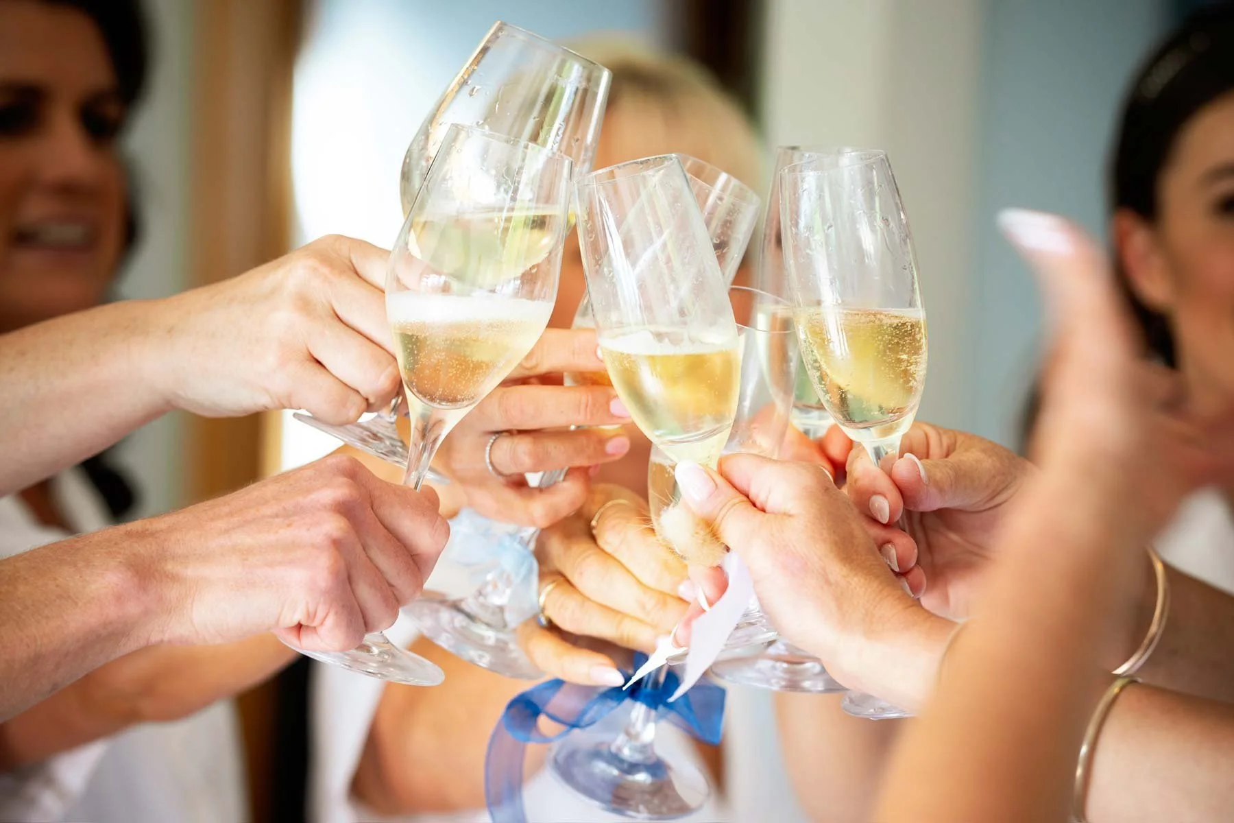 Multiple people raising glasses of champagne in a toast at a celebration.