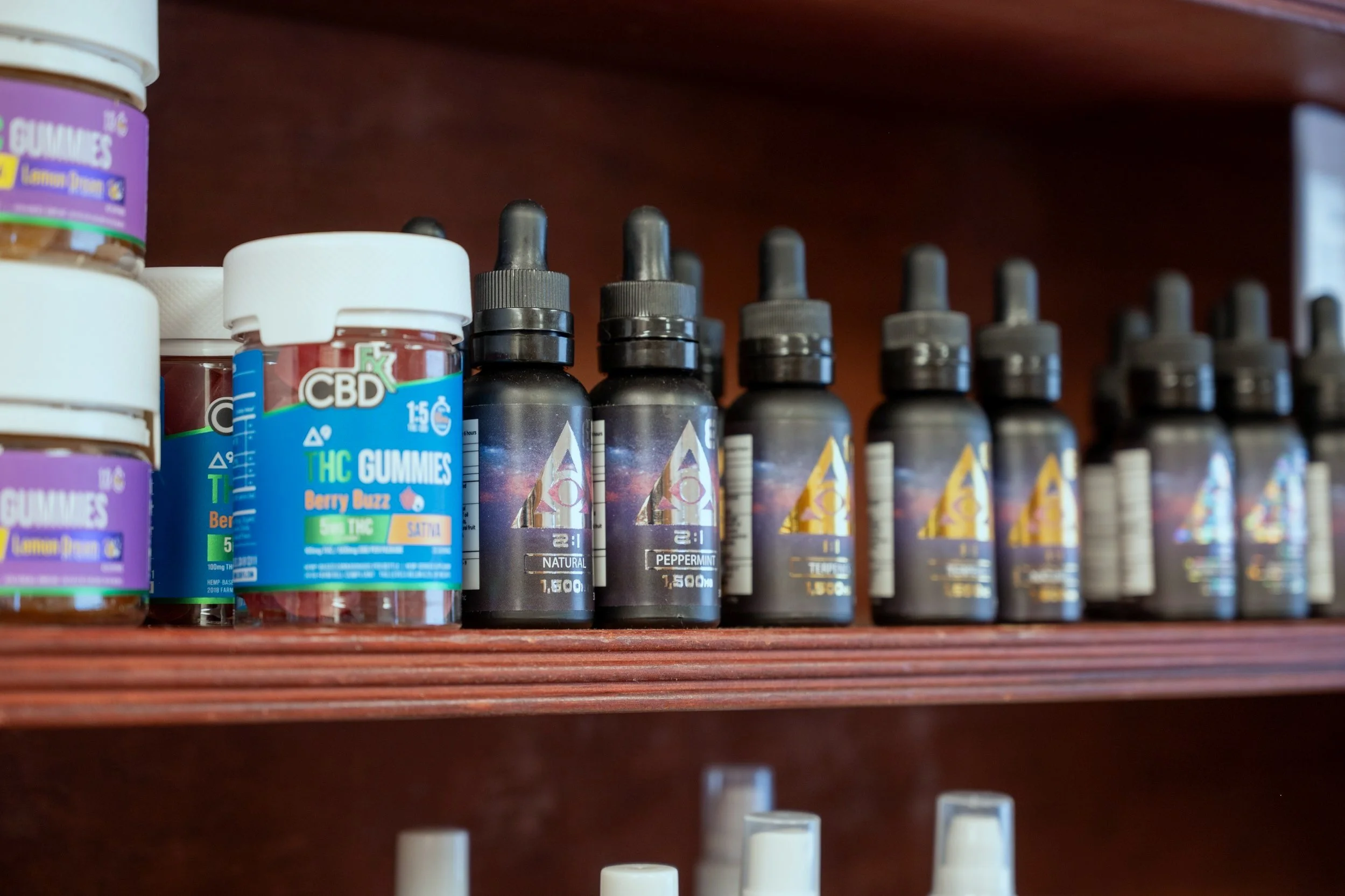 Shelf with CBD gummies, THC gummies, and CBD tincture bottles.