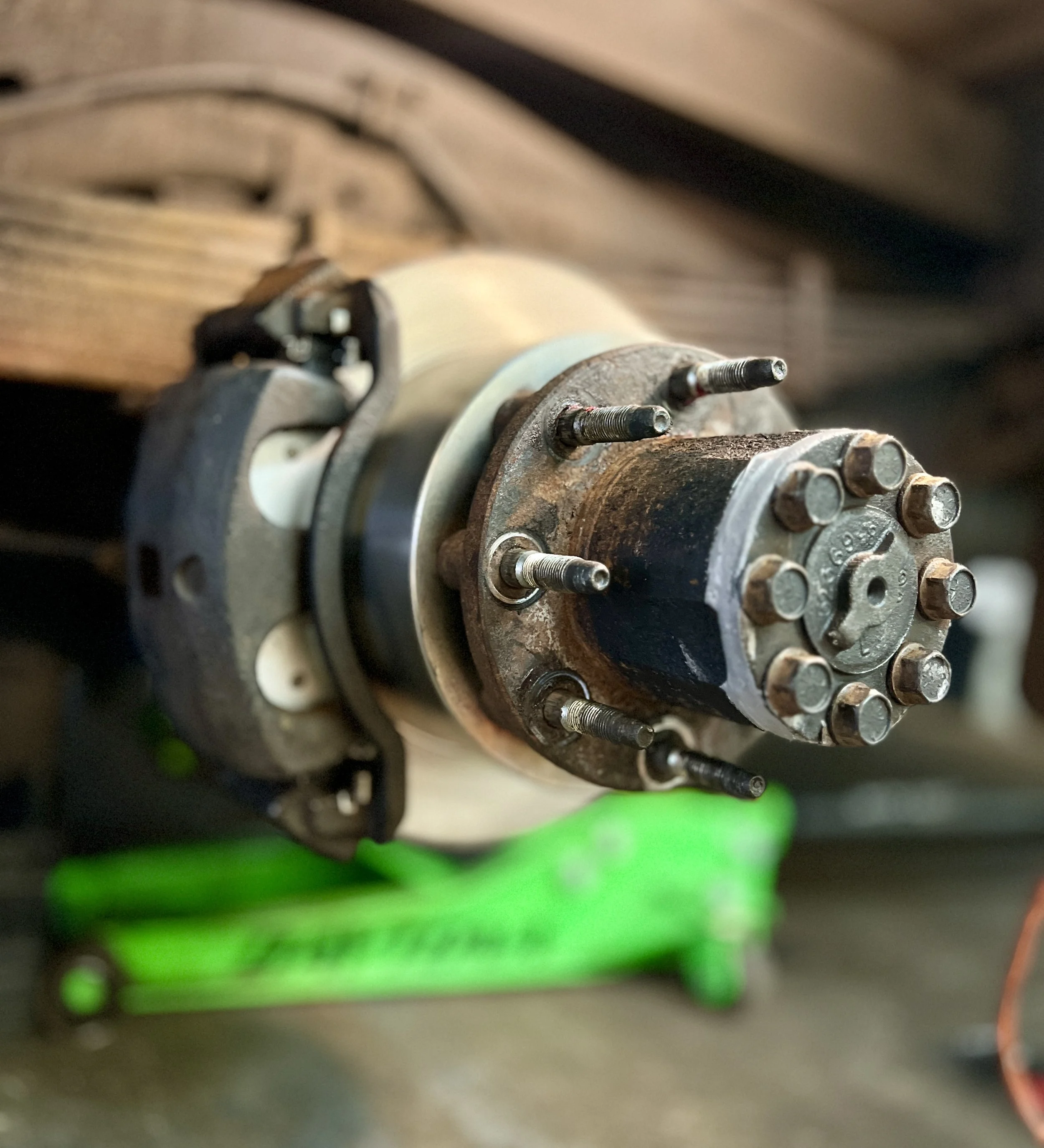 A close-up of a rusty car wheel hub assembly mounted on a workbench, with a green tool in the background .RIFFT FLEET SHOP RIFFT LLC
