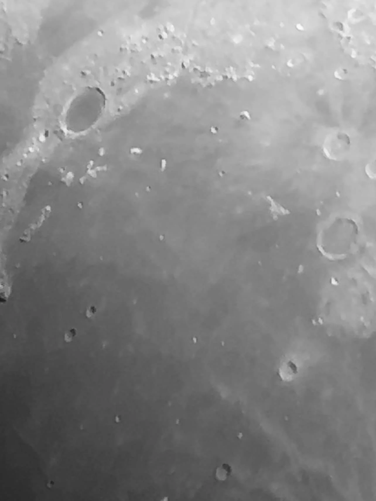 Close-up black and white image of the moon's surface showing craters and rough terrain.