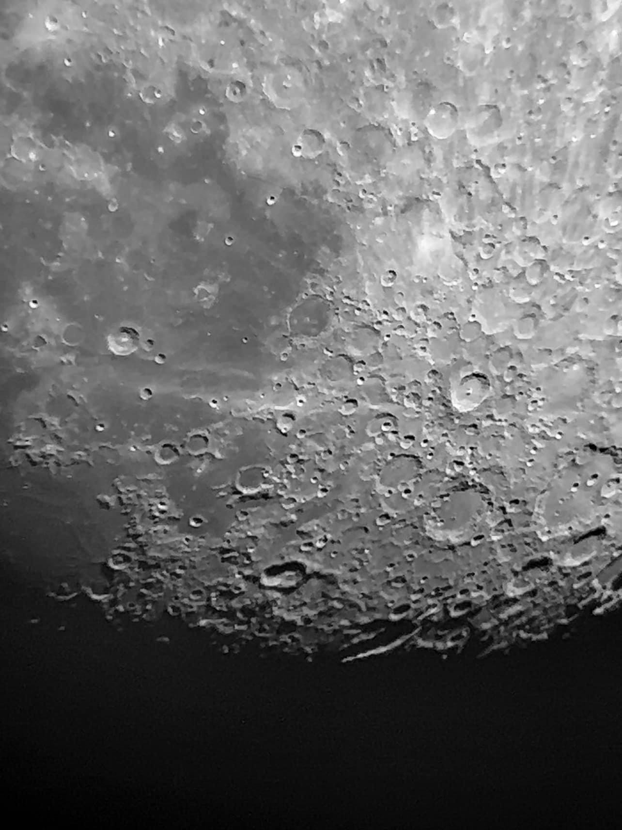 Close-up view of the moon's cratered surface with a dark background.
