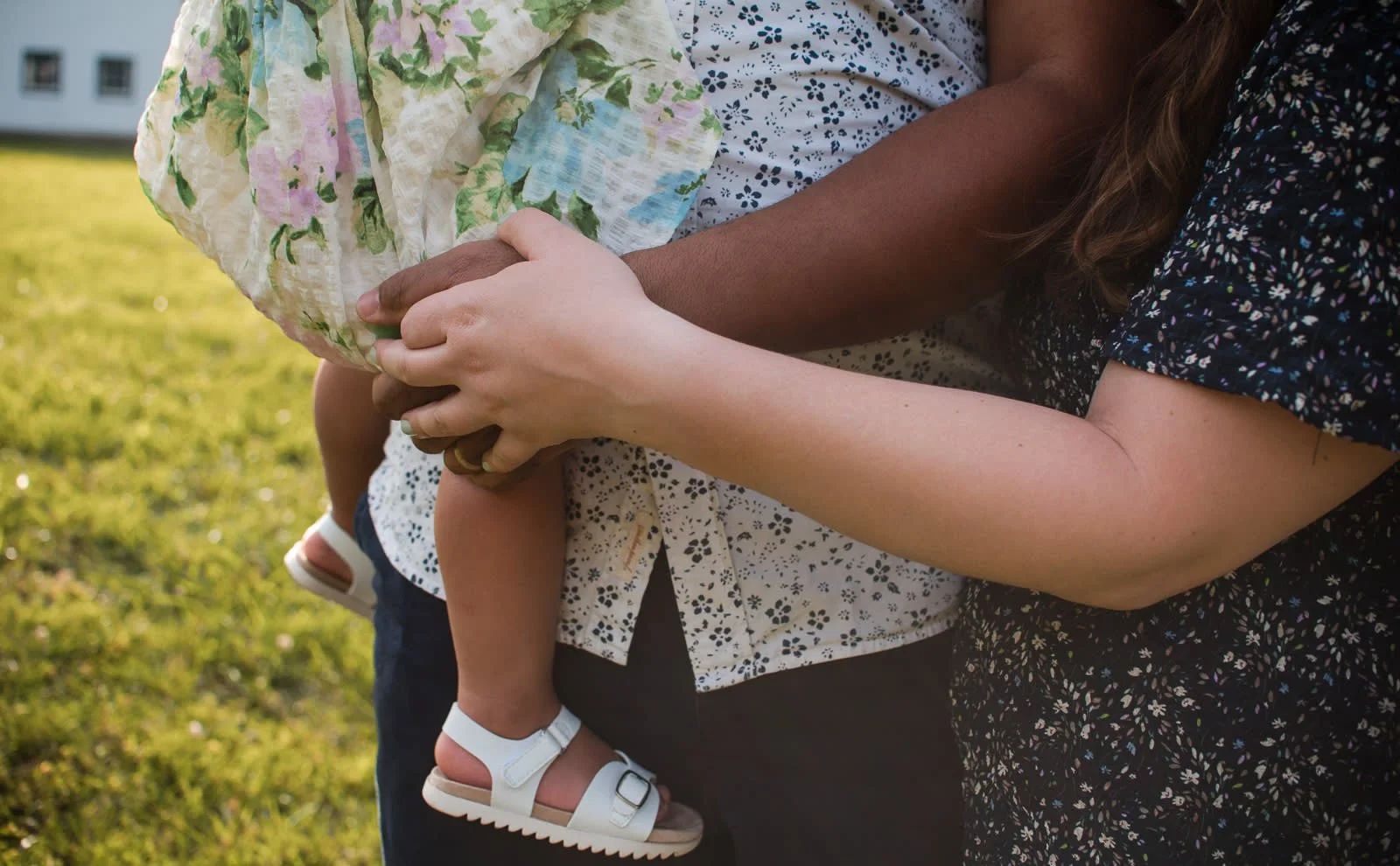 mother and father hold baby while holding hands during a summer sunset family session at Ivy Creek Natural Area in Charlottesville, VA by Erin E Gallagher Photography