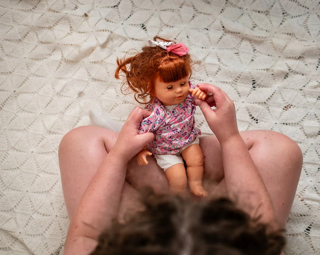 little girl plays with red-haired doll while sitting on the ground by Erin E Gallagher Photography in Charlottesville, VA