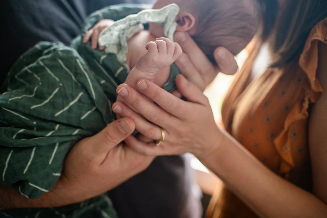 “Newborn lifestyle session in Richmond, Virginia — parents holding their sleeping baby in natural window light, captured by Erin E. Gallagher Photography.”