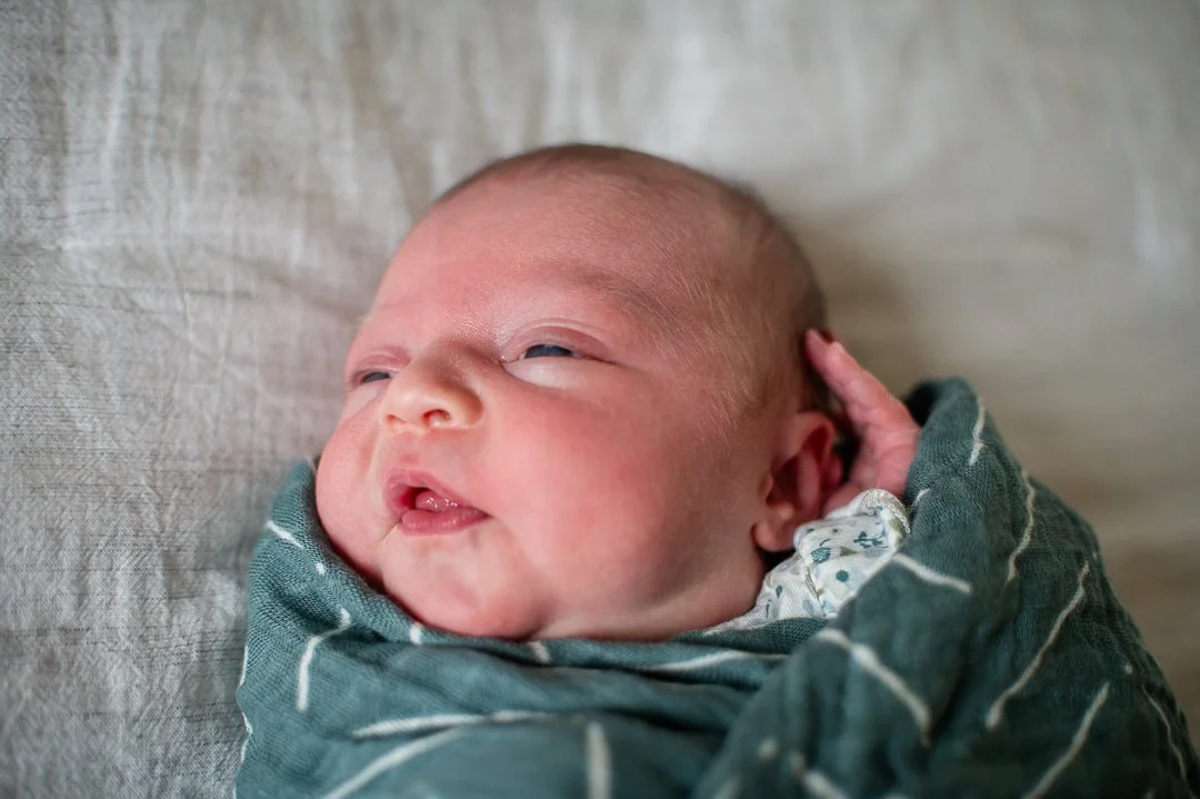 “Newborn lifestyle session in Richmond, Virginia — baby wrapped in a blanket with parents admiring their first moments together.”