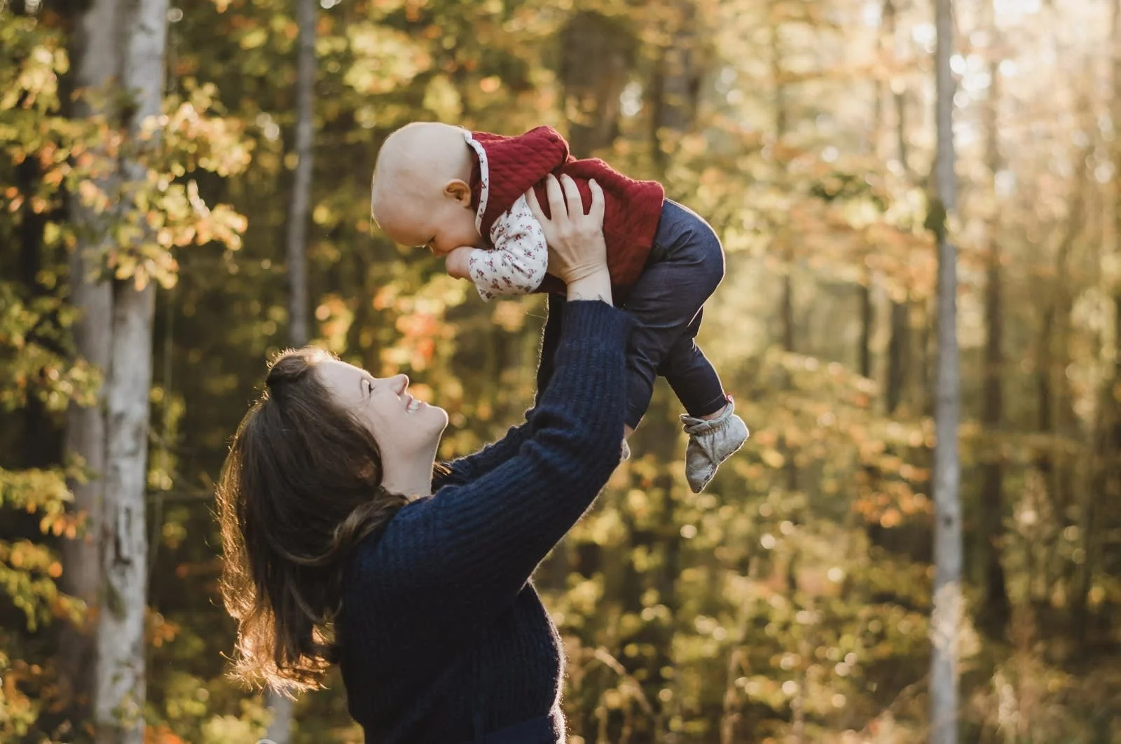 mom holding infant up in the air and smiling during fall family pictures in central va by Erin E Gallagher Photography