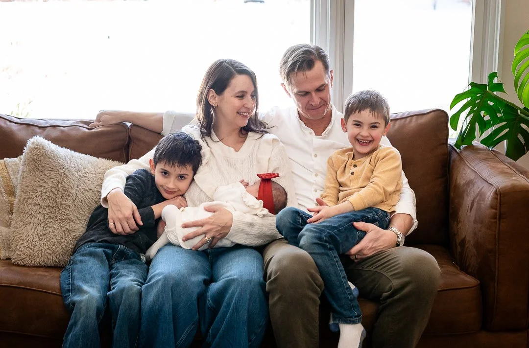 mother, father, newborn, 2 sibling brothers sitting on couch looking at each other during newborn session by Erin E Gallagher Photography in Waynesboro, VA