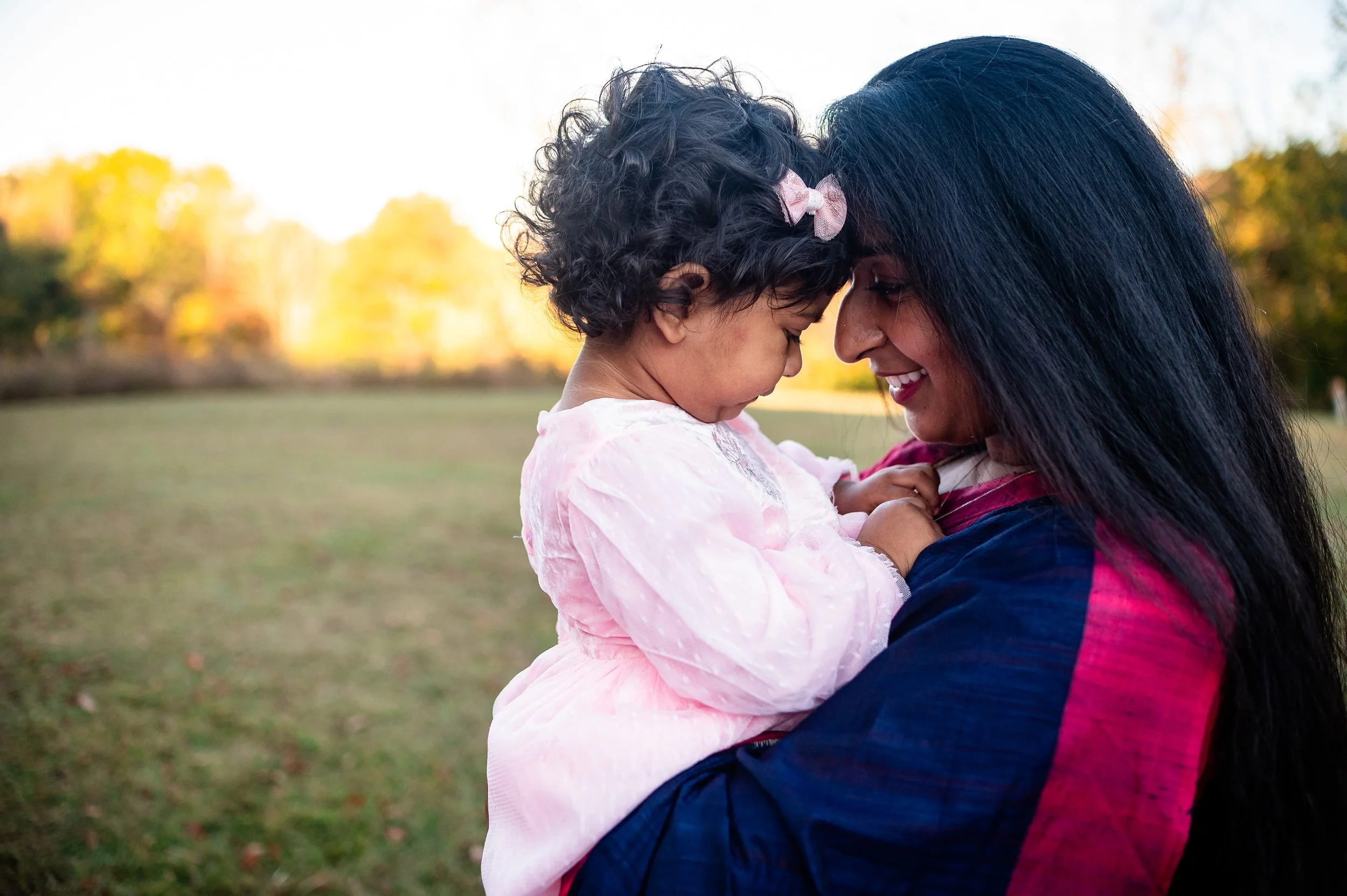 picture of mother holding toddler daughter smiling while foreheads are touching in an outdoor spring family session in Richmond, VA by Erin E Gallagher Photography