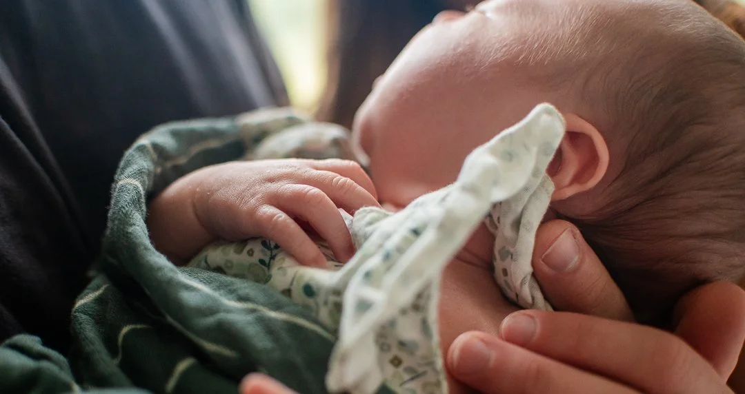 “Newborn lifestyle session in Richmond, Virginia — parents holding their sleeping baby in natural window light, captured by Erin E. Gallagher Photography.”