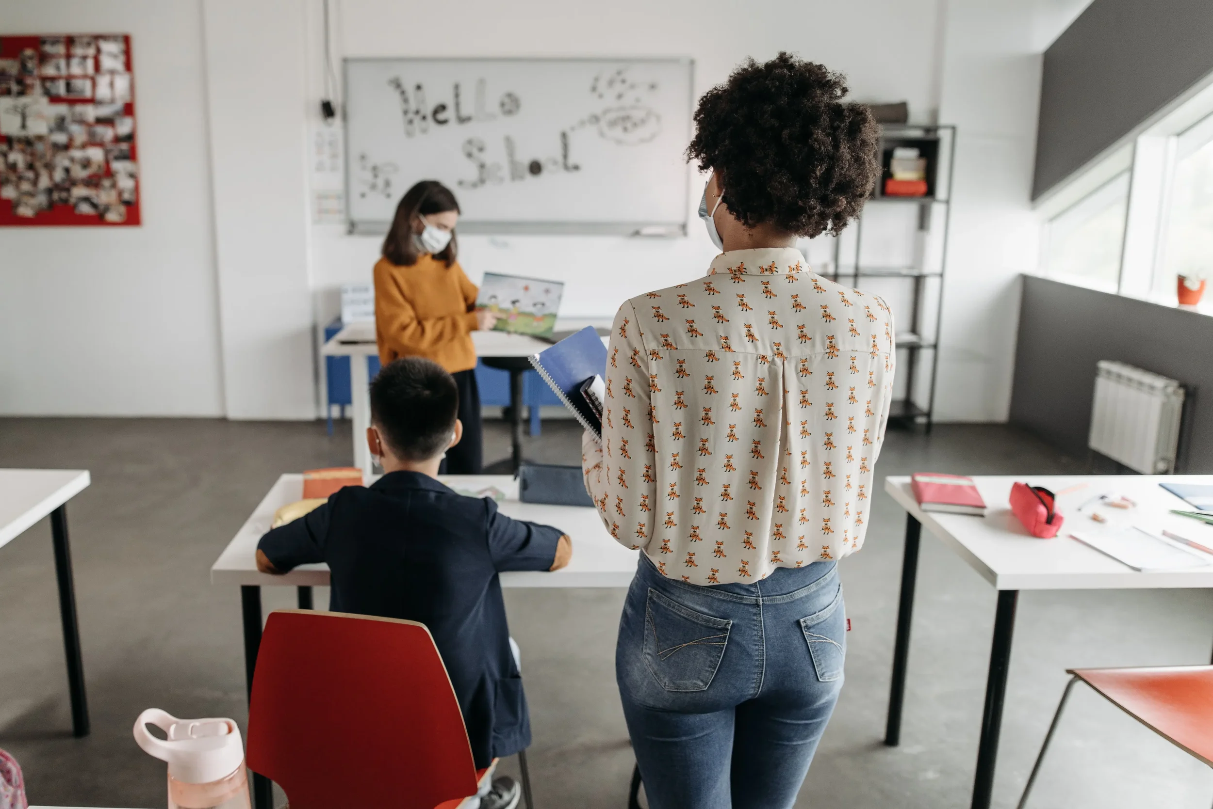 Educators in a classroom with a student, representing back-to-school mental health workshop topics therapists can offer schools and parent groups. 