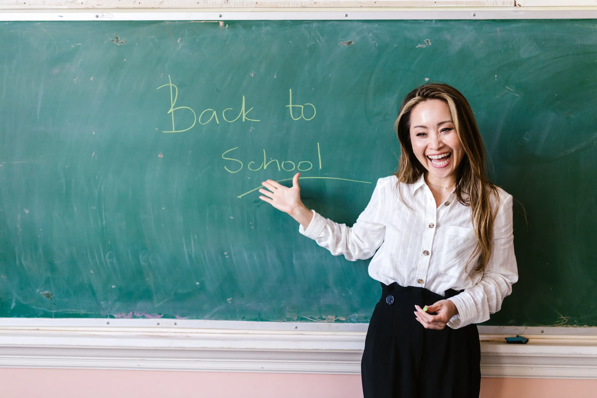 Woman presenting beside a “Back to School” chalkboard, representing therapist referral packet outreach to schools and school counselors.