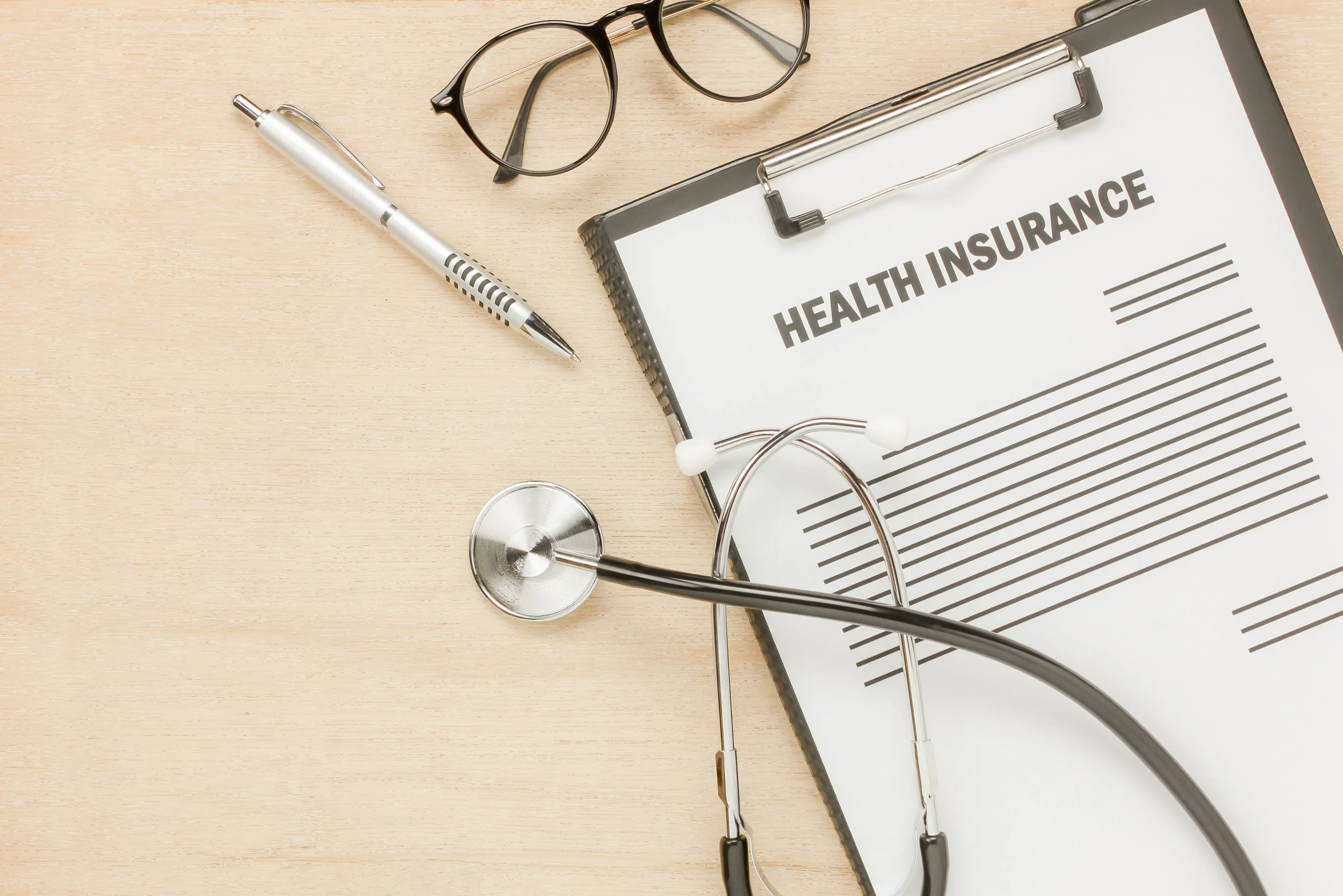 An image of a pen, stethoscope and a health insurance clipped on a clipboard - The Private Practice Pro