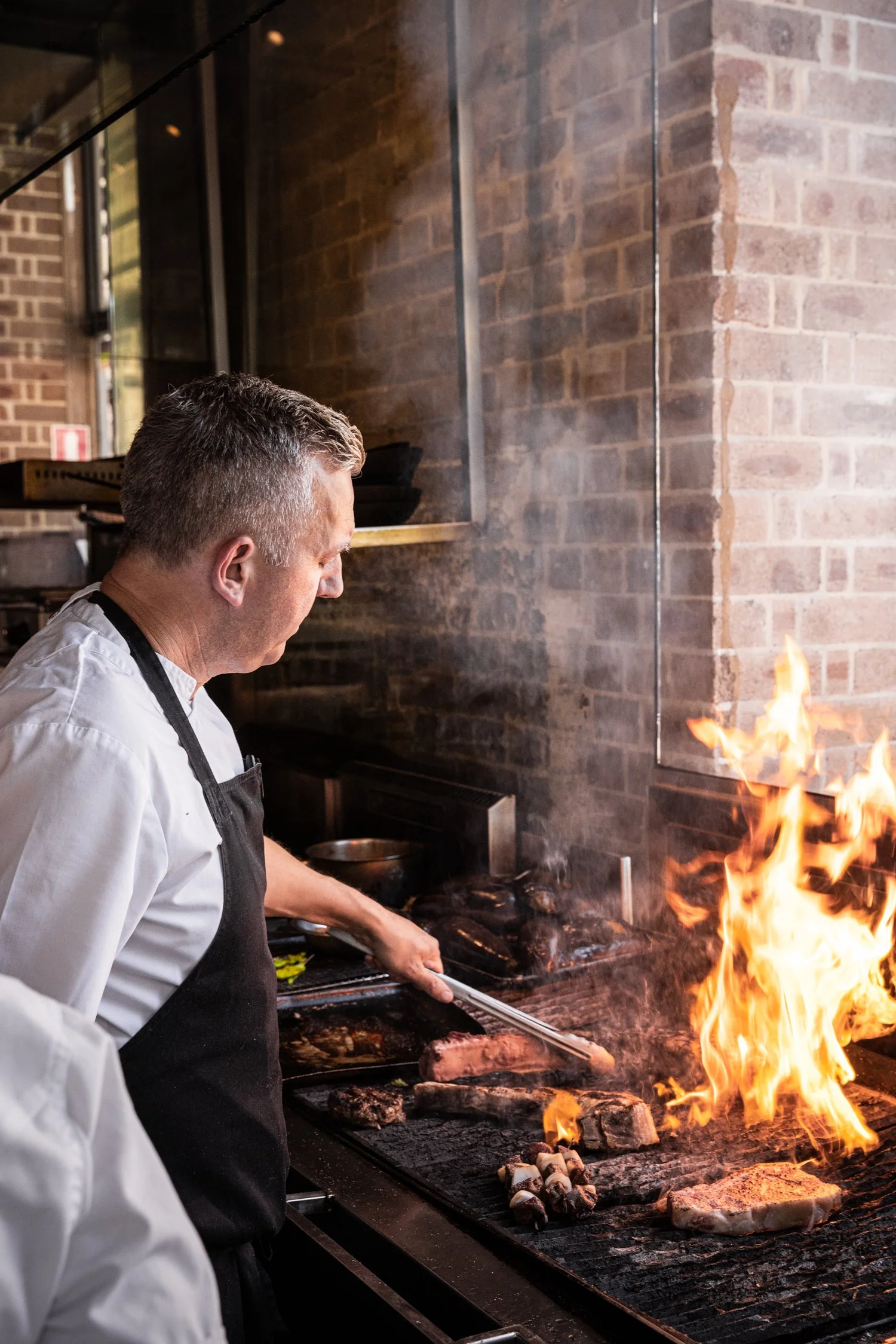Head Chef at Pony Dining cooking premium steak cuts over the wood fire grill