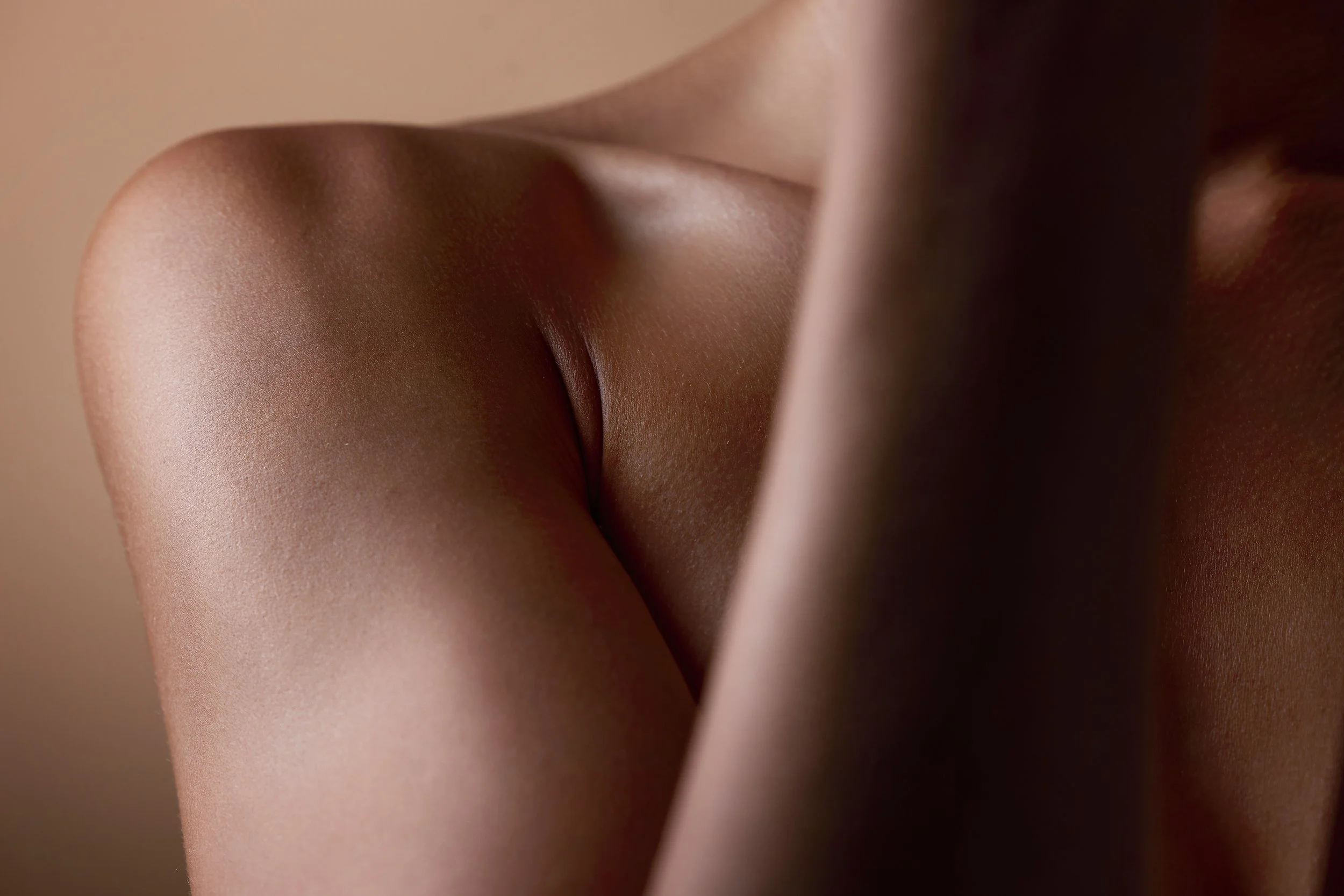 Close-up of a person's back and shoulder with smooth skin, showing subtle shadows and highlights