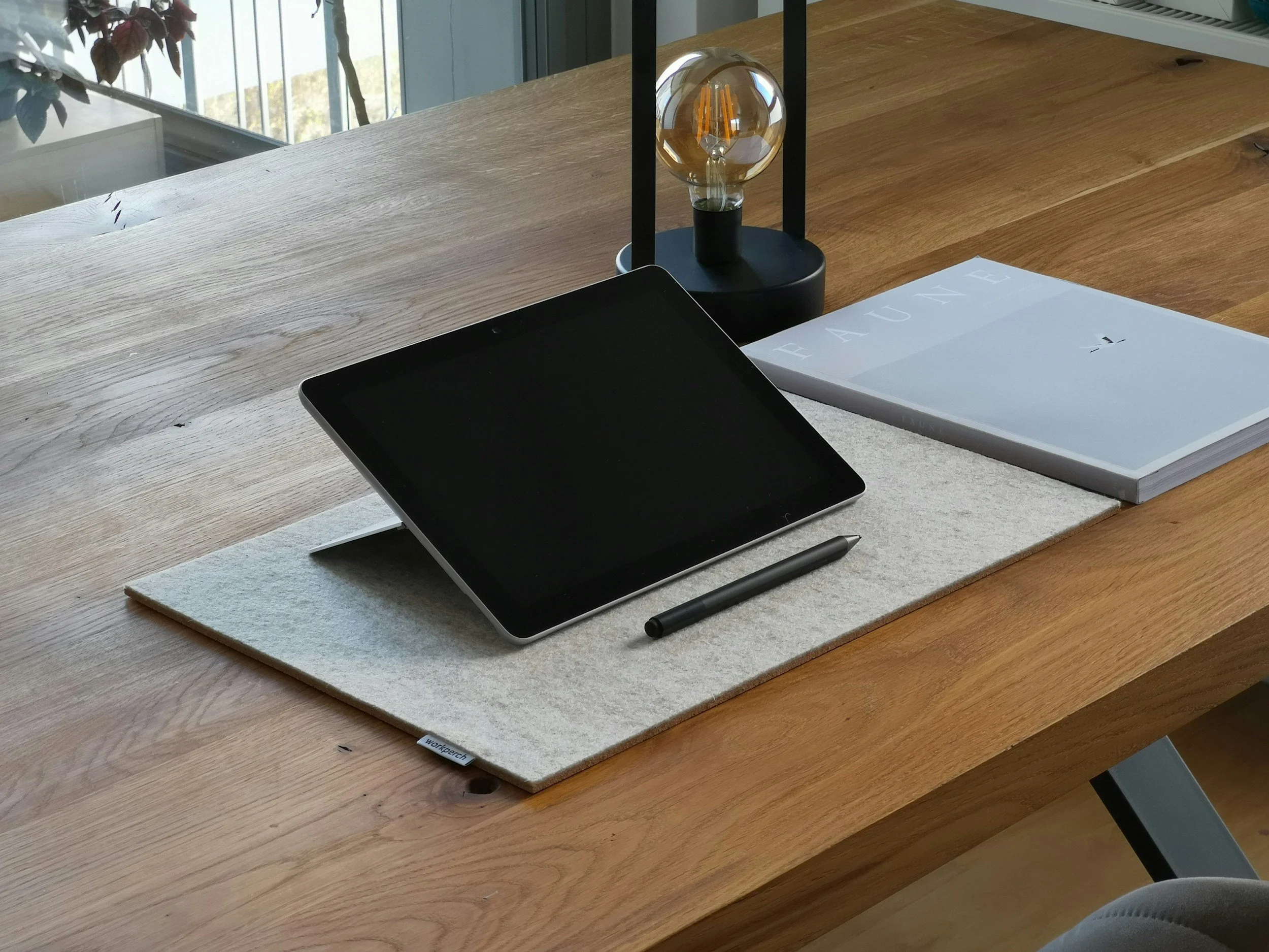 Tablet and pen arranged on a clear wooden workspace.