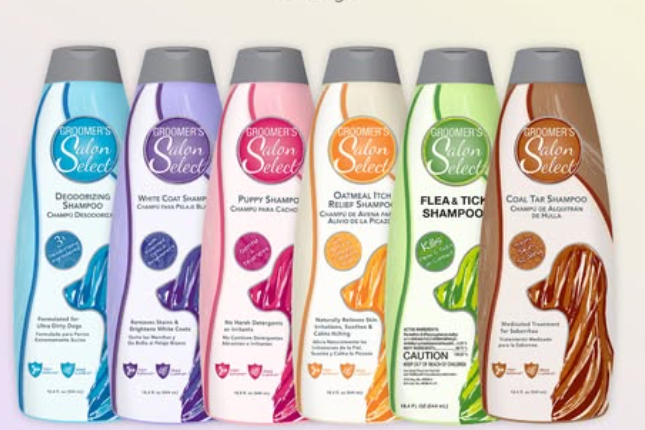 Six bottles of Groomer's Salon Select dog shampoos in various colors, including deodorizing, white coat, puppy, oatmeal, flea and tick, and coal tar formulas.