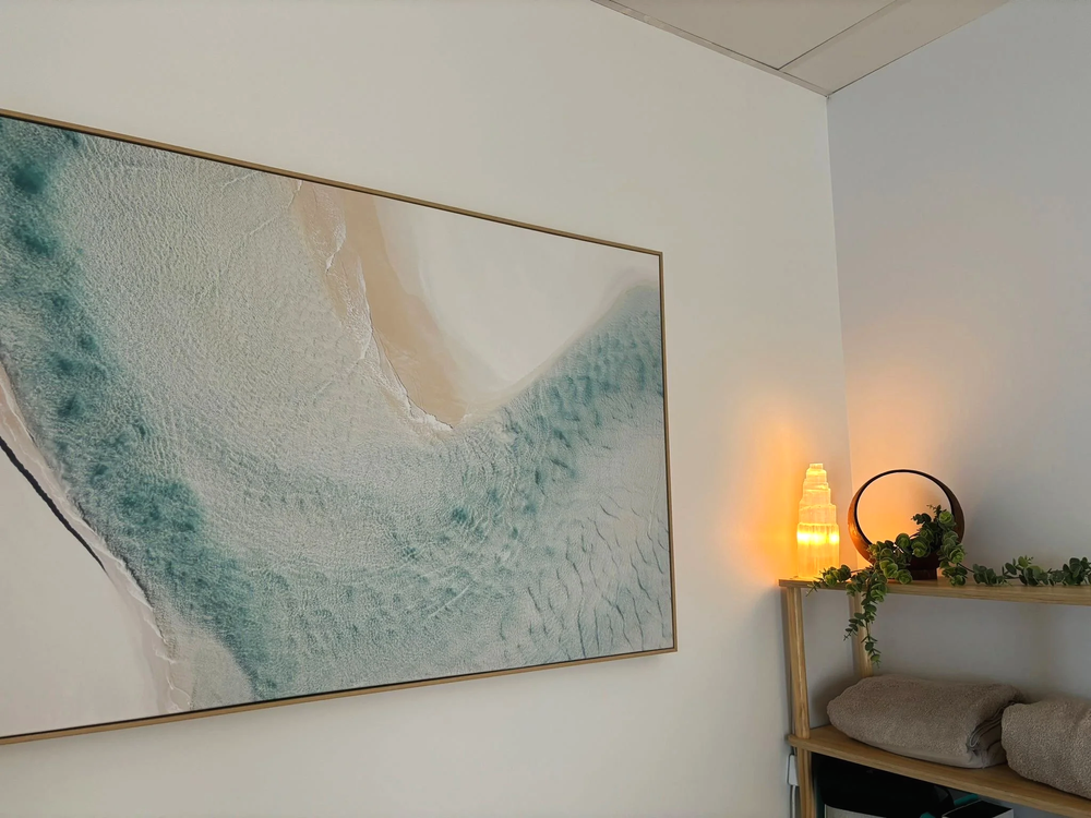 Treatment room with armchair, lamp and coastal wall art at Bellarine Wellness Co in Queenscliff.