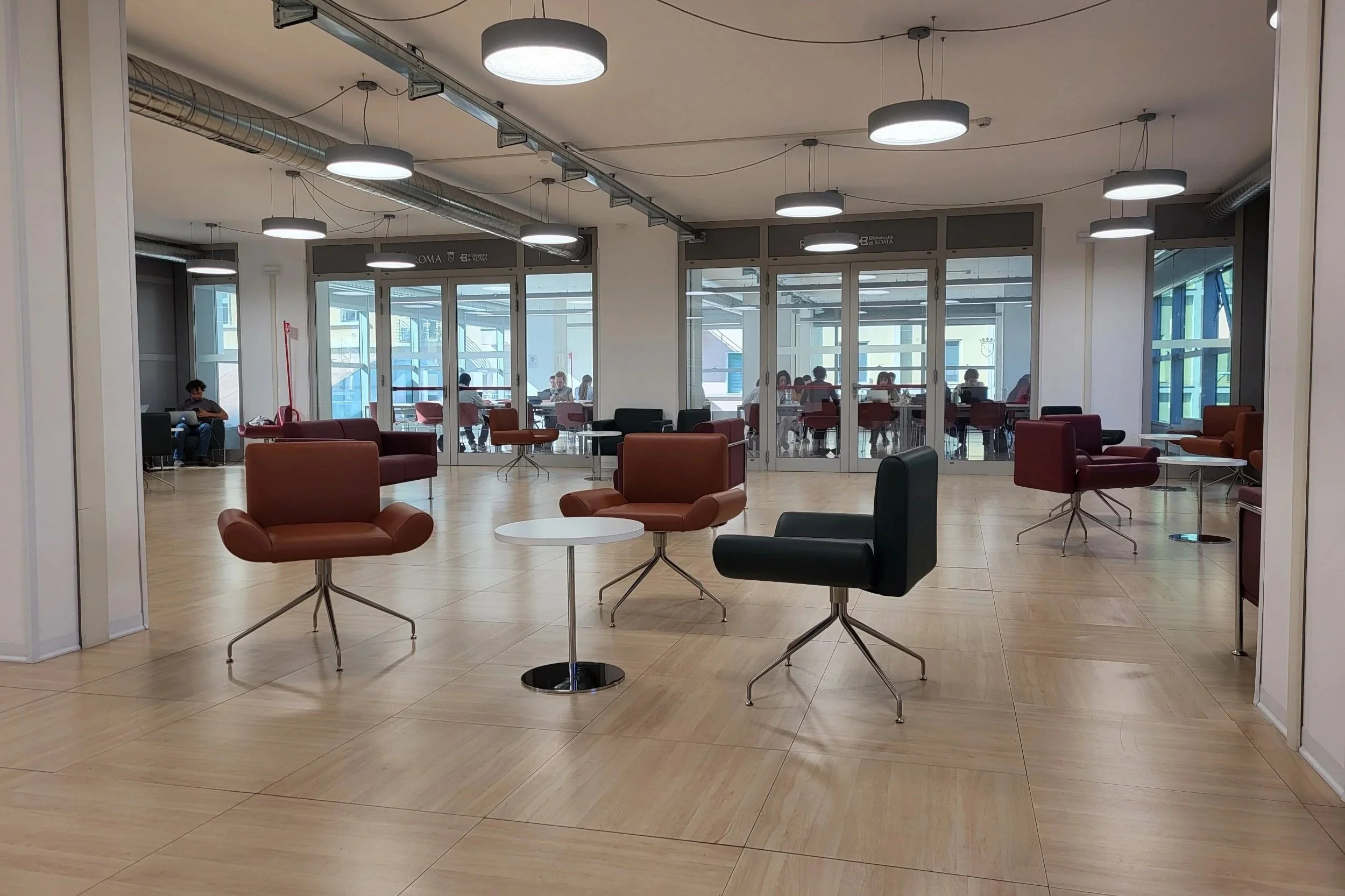 The study room of Aula Studio Trionfale with many chairs and people studying.