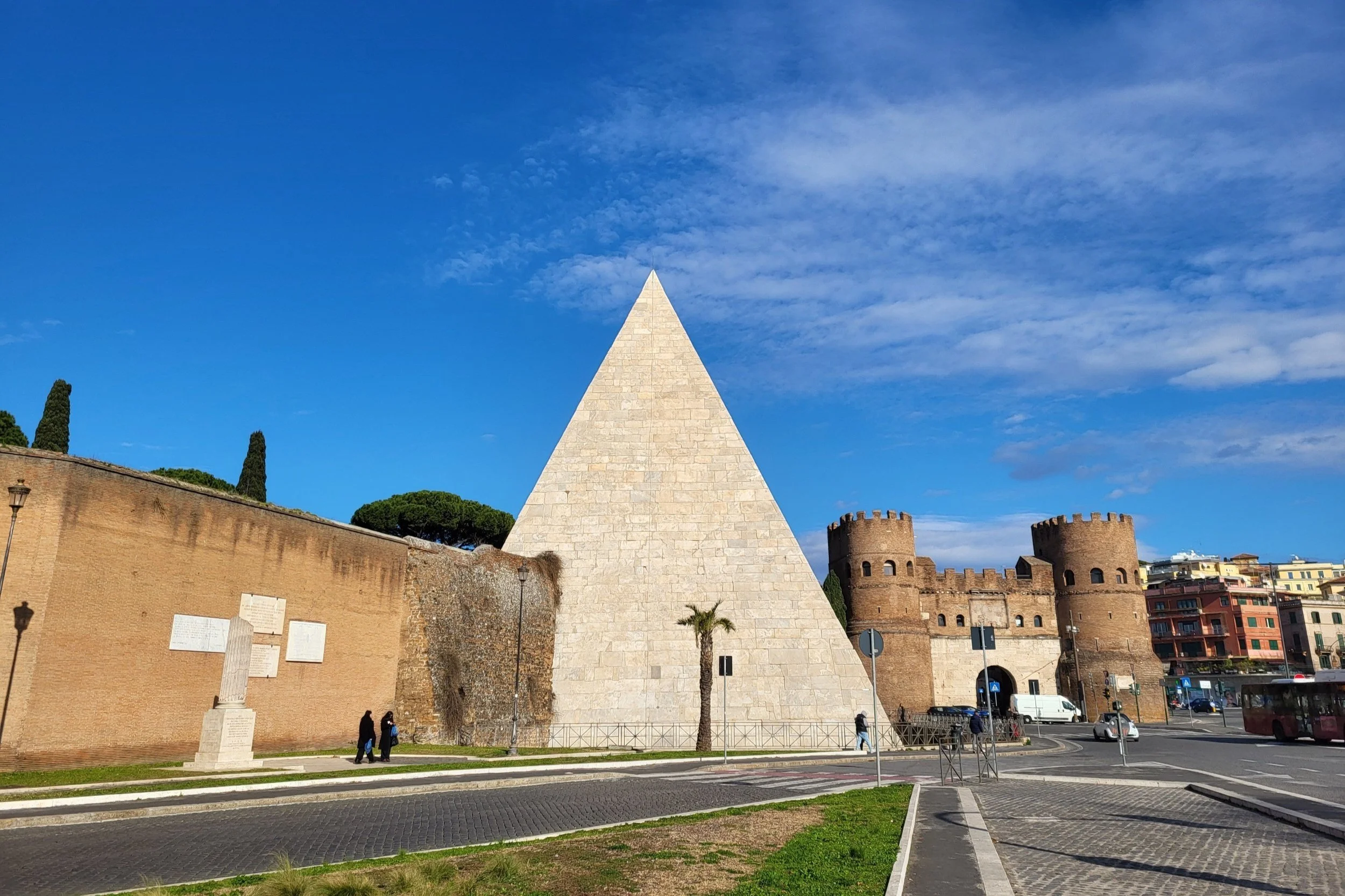 The ancient Pyramid of Cestius in Ostiense, Rome, standing tall against a bright blue sky.