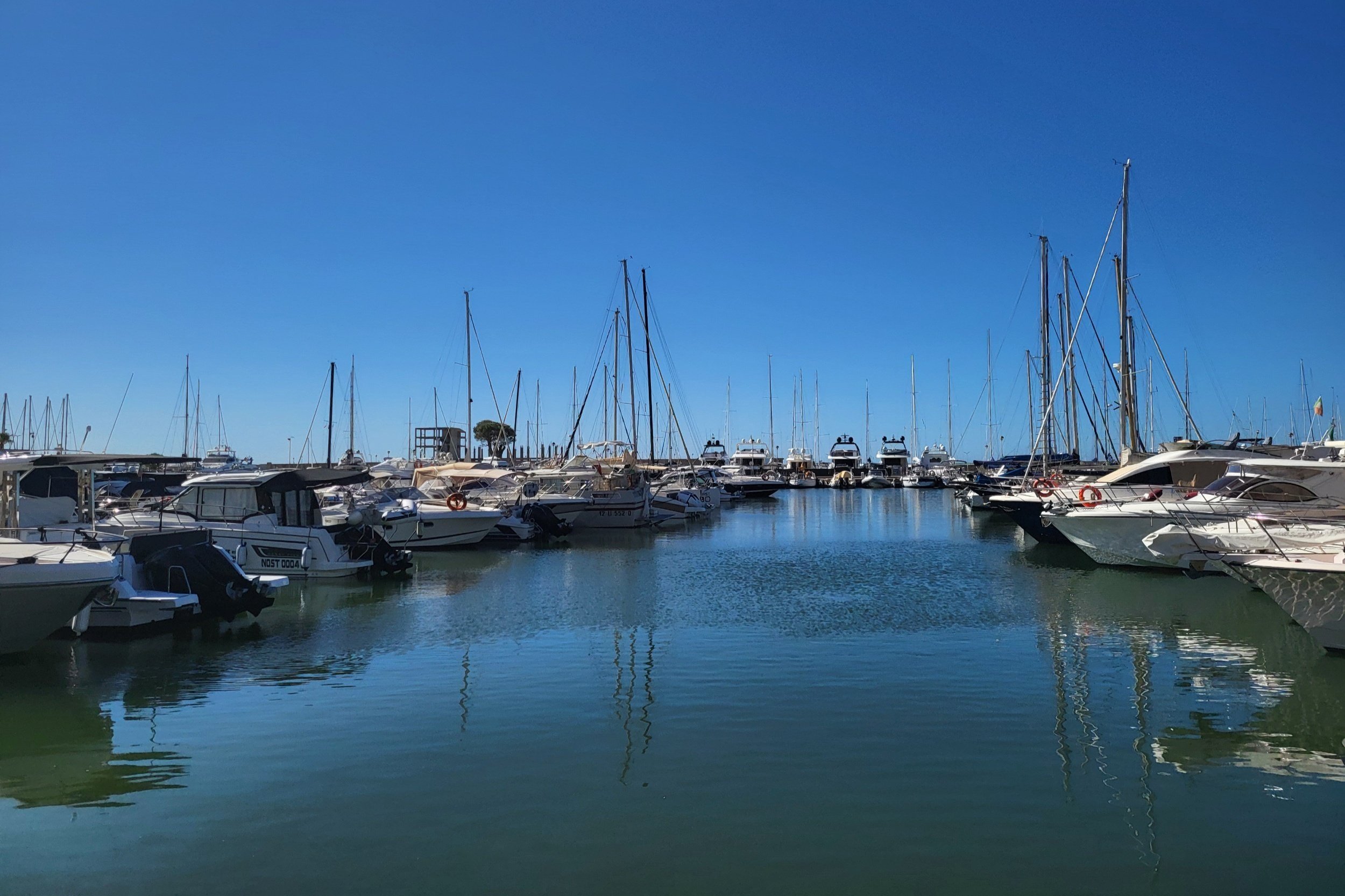 View of Nettuno’s harbor with small boats and calm water on a warm day