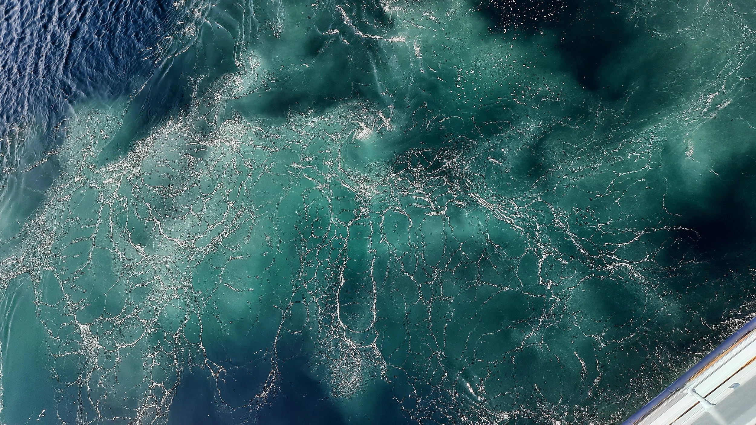 Für den Titanic Podcast "tiTENic minutes": Eine verwirbelte Wasseroberfläche mit türkis-weißen Farbtönen