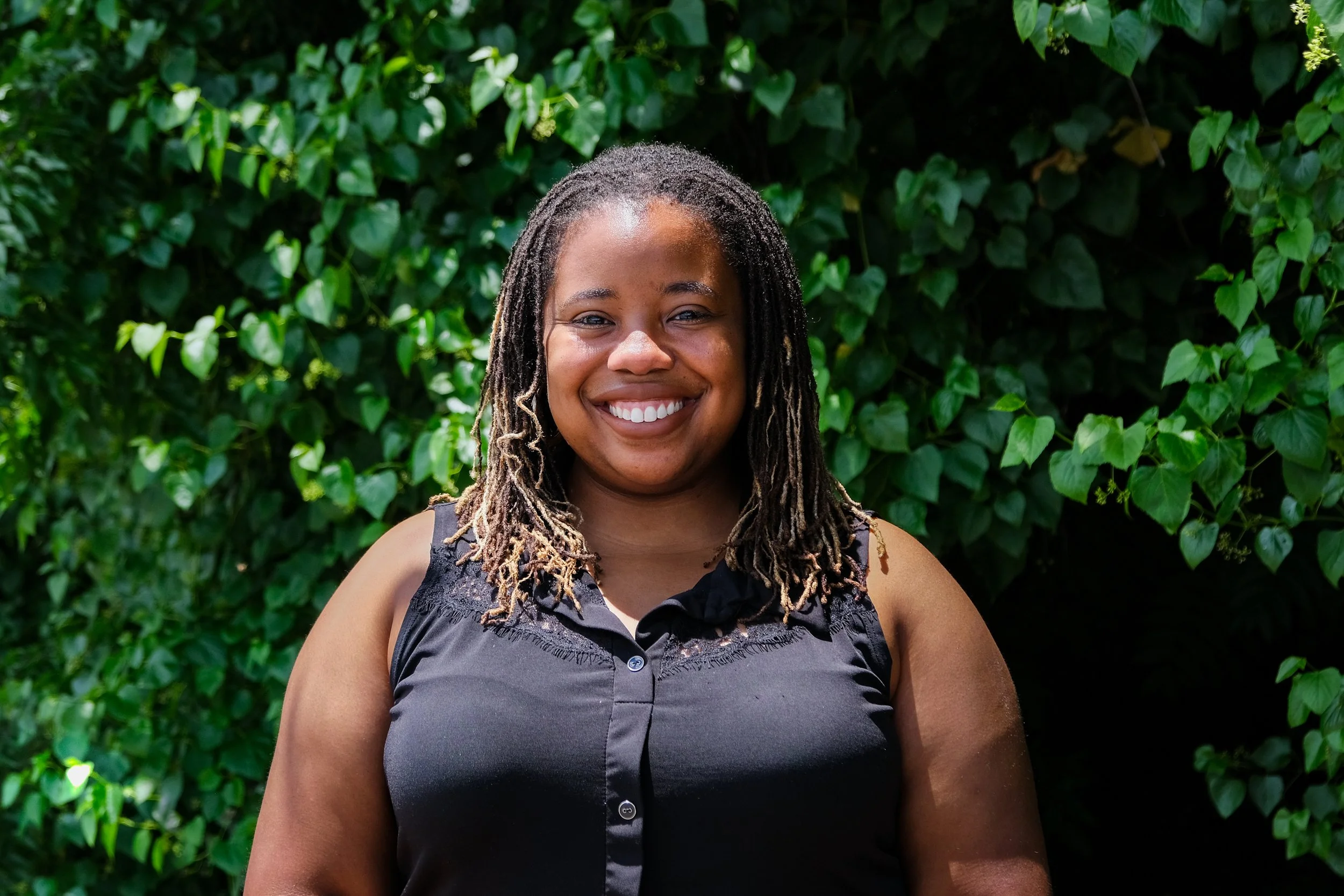 Briana Perry is a Black woman with micro locks and a black tank top on