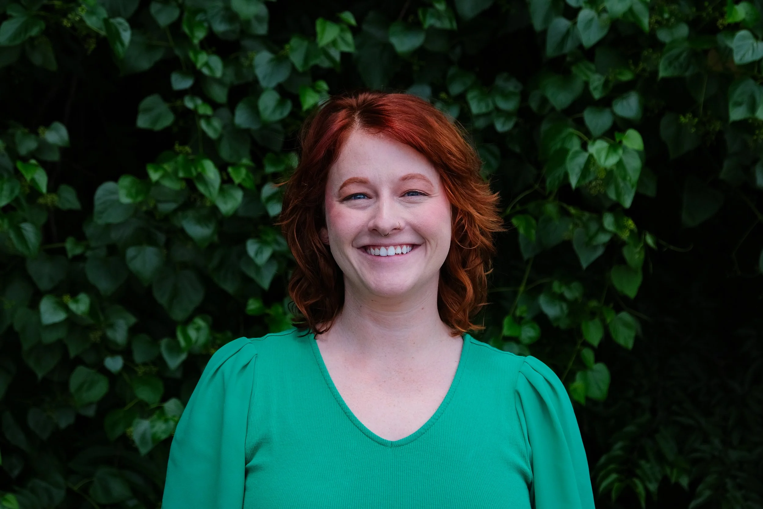 Elise is a white woman with red hair and a green top