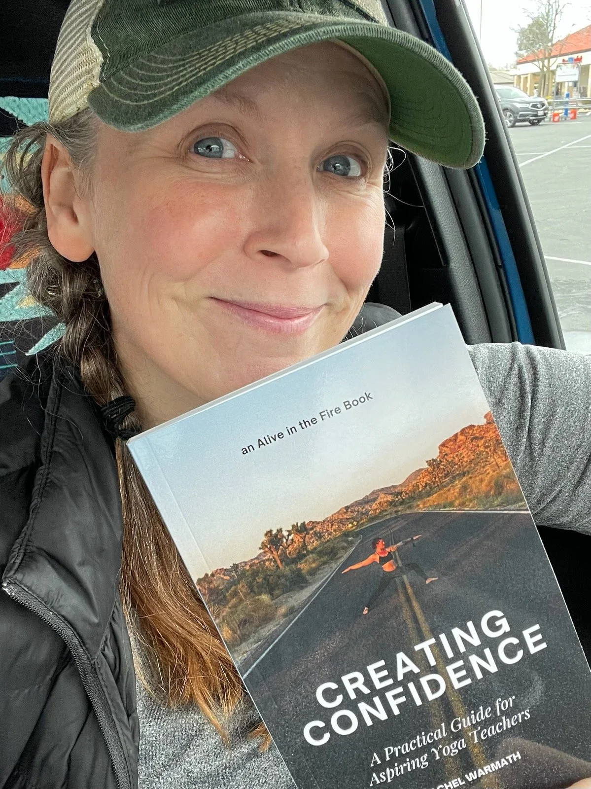 A yogi holding a copy of Creating Confidence by Rachel Warmath