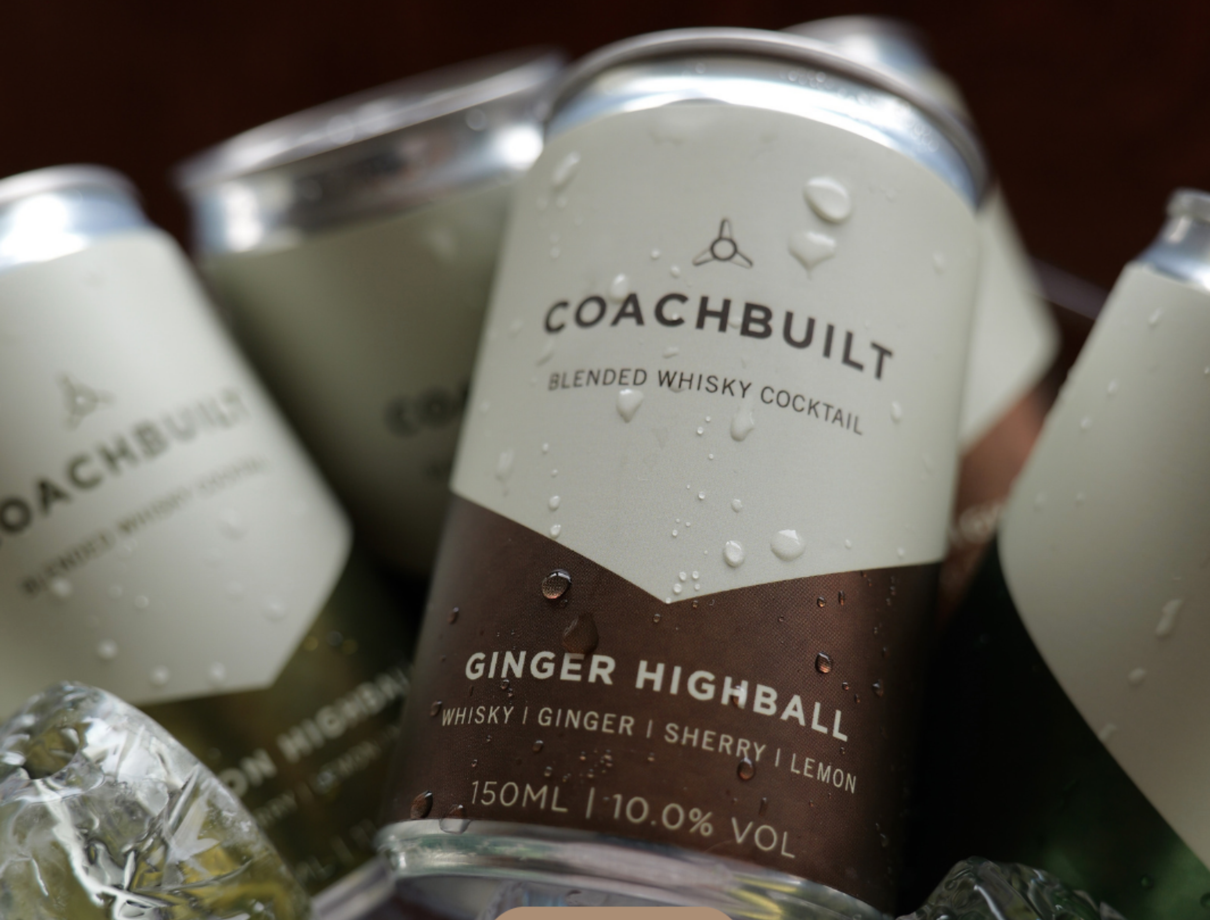 Close-up of a bottle labeled 'Coachbuilt Ginger Highball' with water droplets on its surface, surrounded by ice cubes.