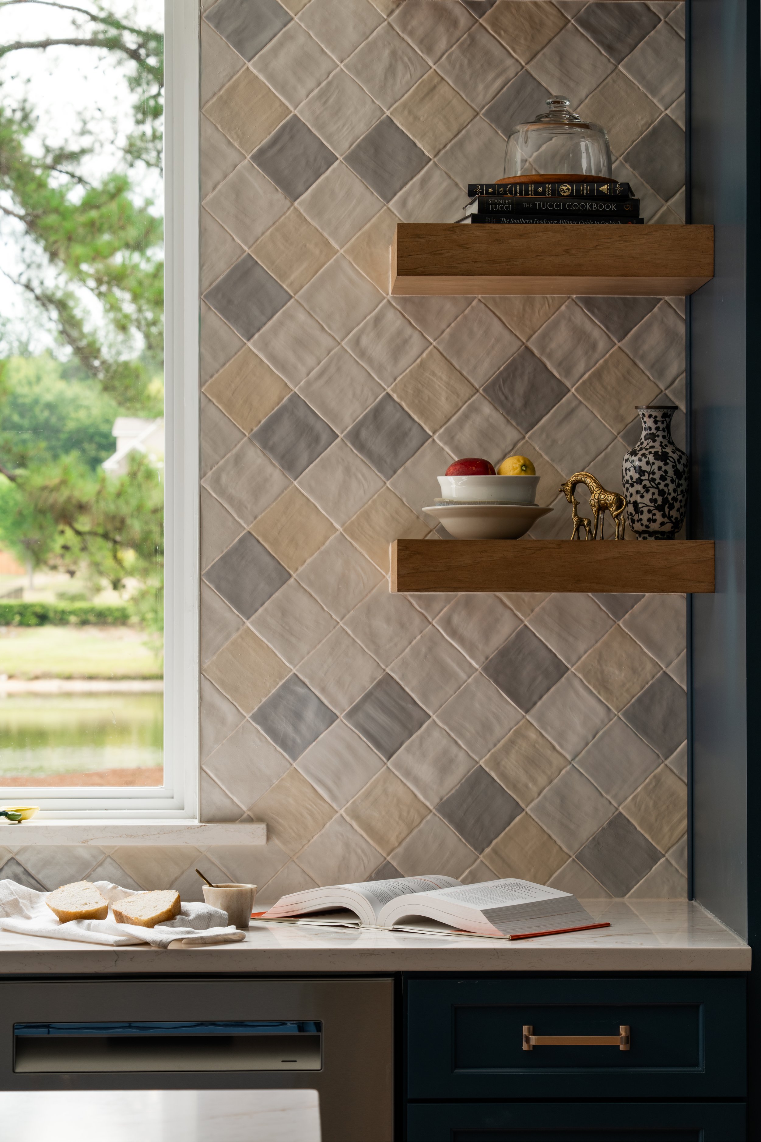 Kitchen countertop with breakfast items, an open book, and a window overlooking trees.