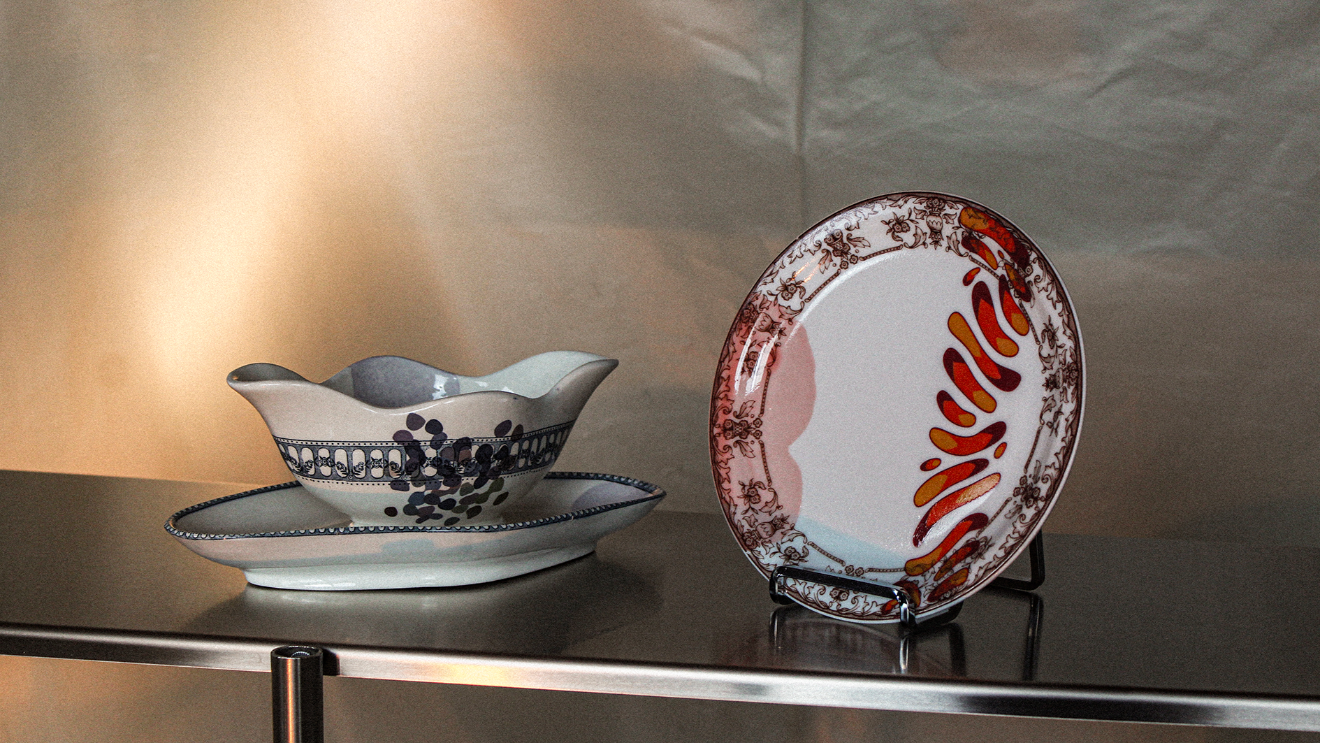Collection de vaisselle en porcelaine, comprenant un plat et deux bowls, avec des motifs colorés et détaillés, exposés sur un support.