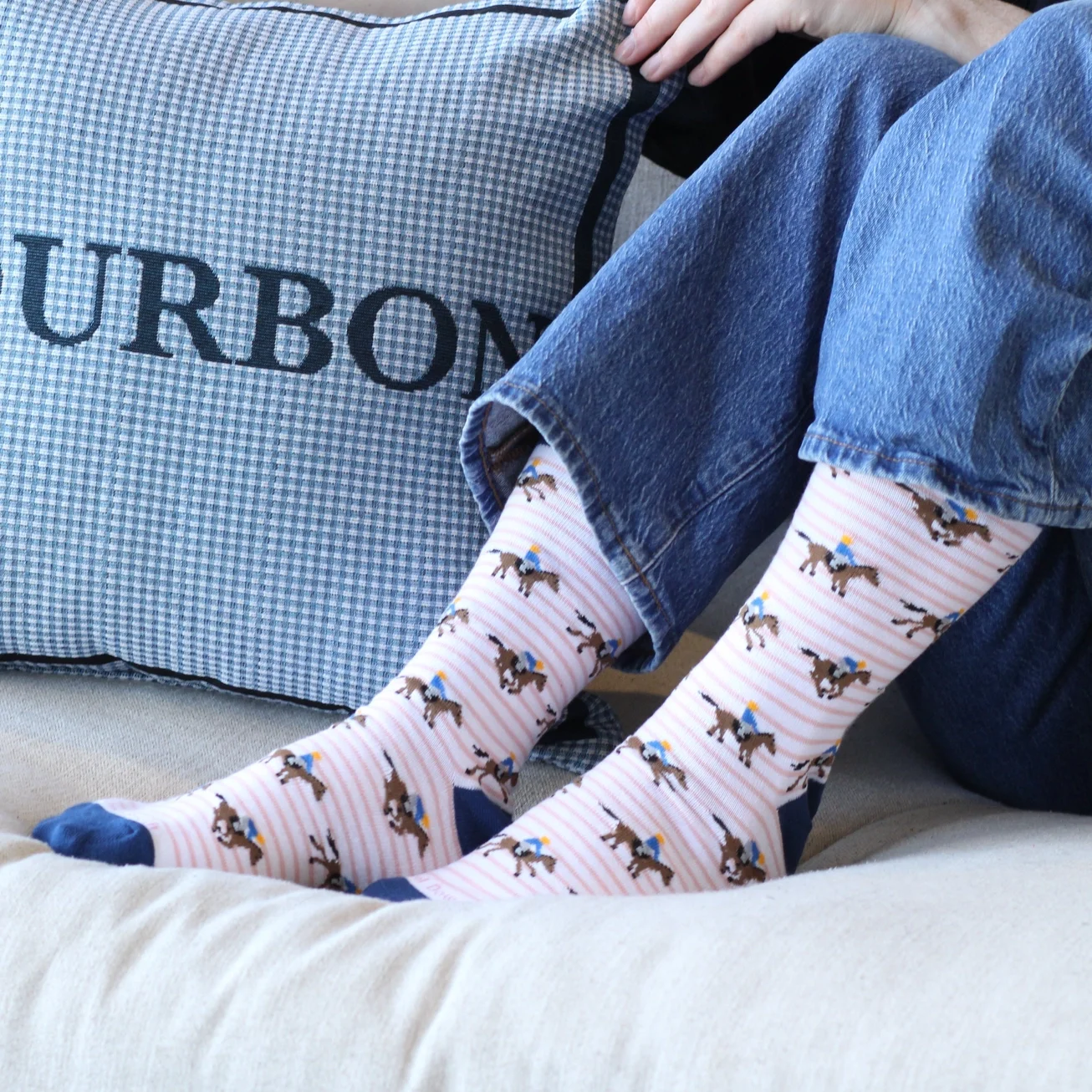 Pink and navy horse racing socks with jockey and racehorse pattern worn with jeans