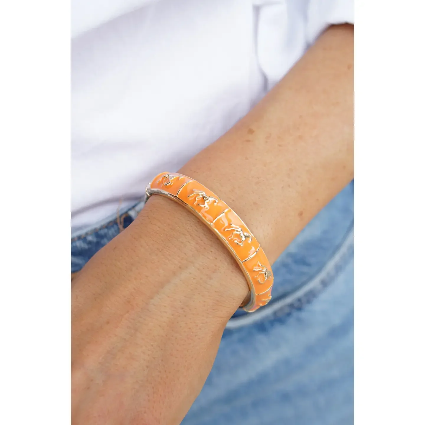 Model wearing Horsin' Around Sculpted Enamel Hinge Bangle bracelet in orange