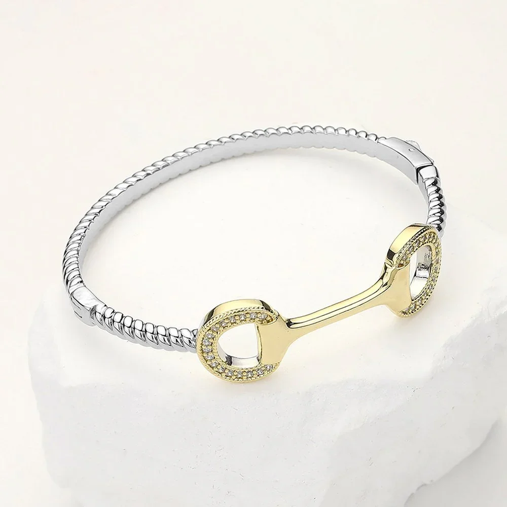 A two-tone bracelet featuring gold and silver with a decorative clasp.