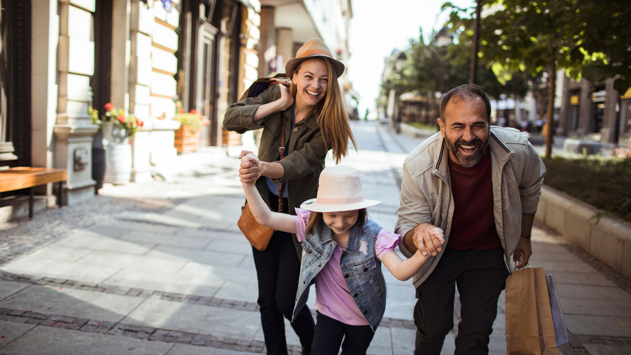 Happy family enjoying time together while walking through city shopping district on sunny day