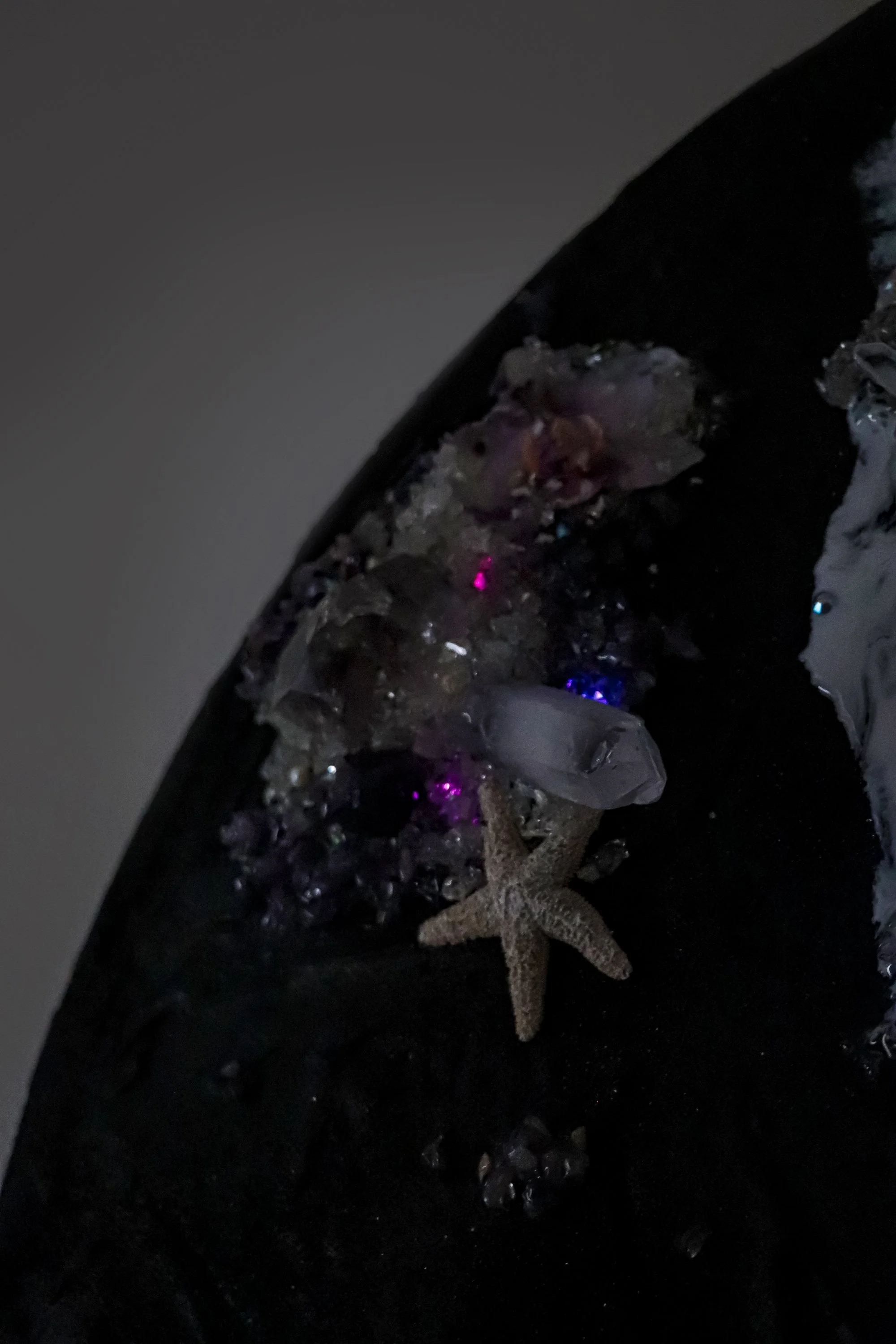 close up detail photo of dark painting, with glowing fiber optic light, quartz crystal and starfish