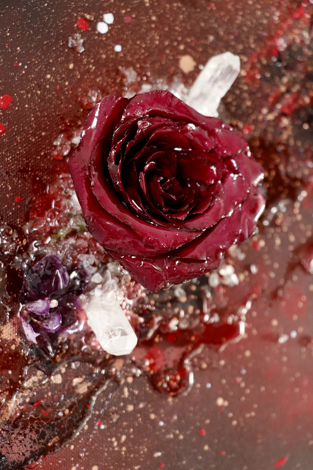 A close up of a luxury abstract painting, with red textured paint, a real preserved red rose, small dark purple orchid and quartz crystal 