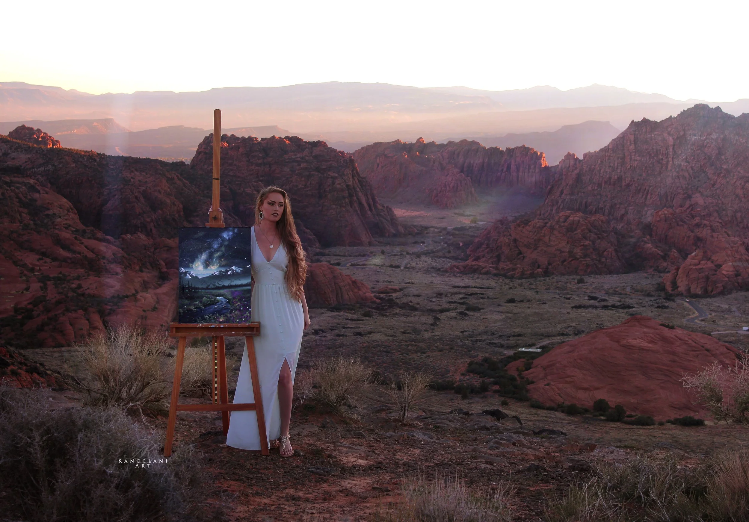 woman standing next to a painting, with the southern utah desert view, snow canyon