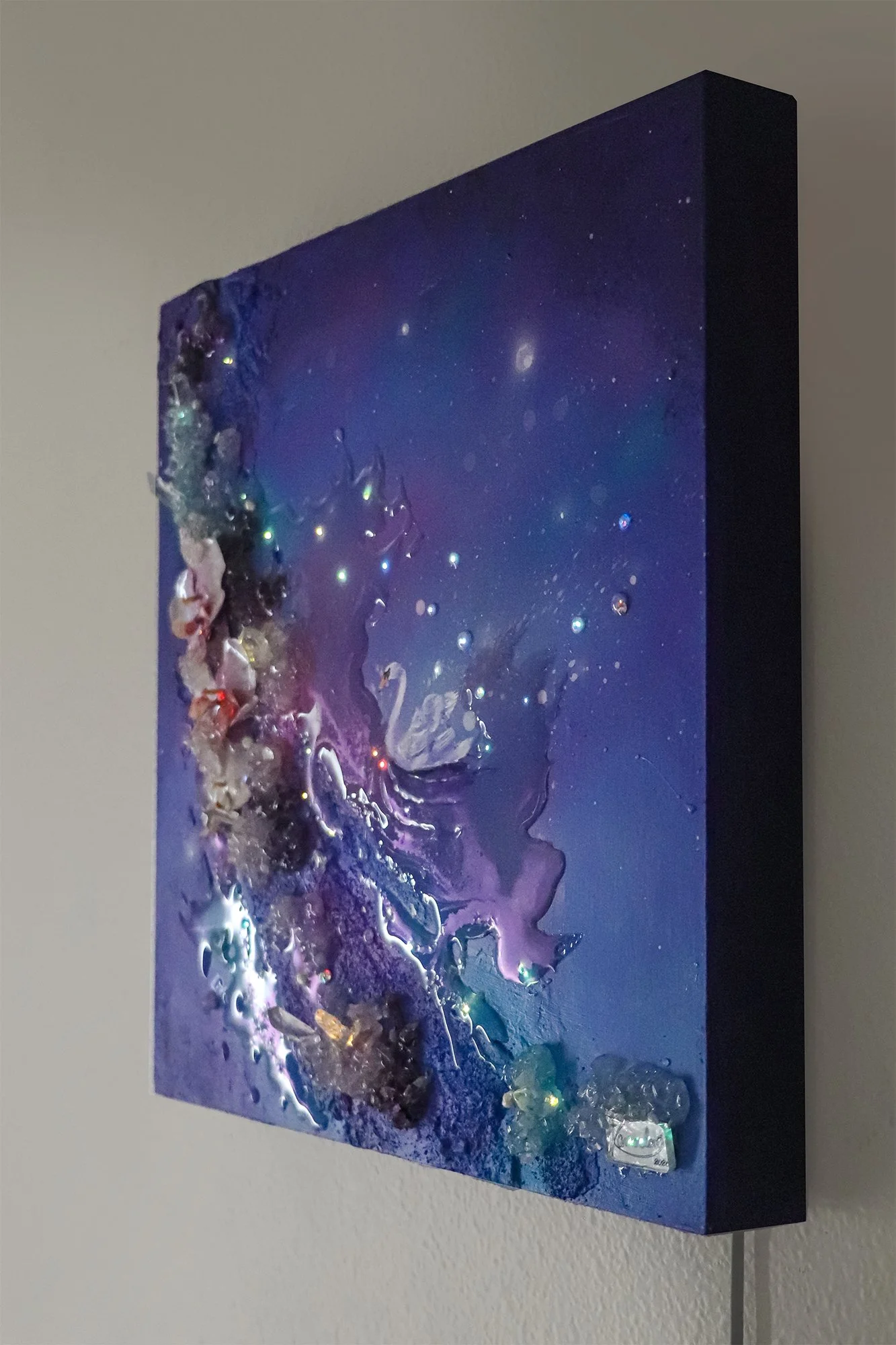 side photo of swan art hanging on a wall, with quartz crystals and orchids