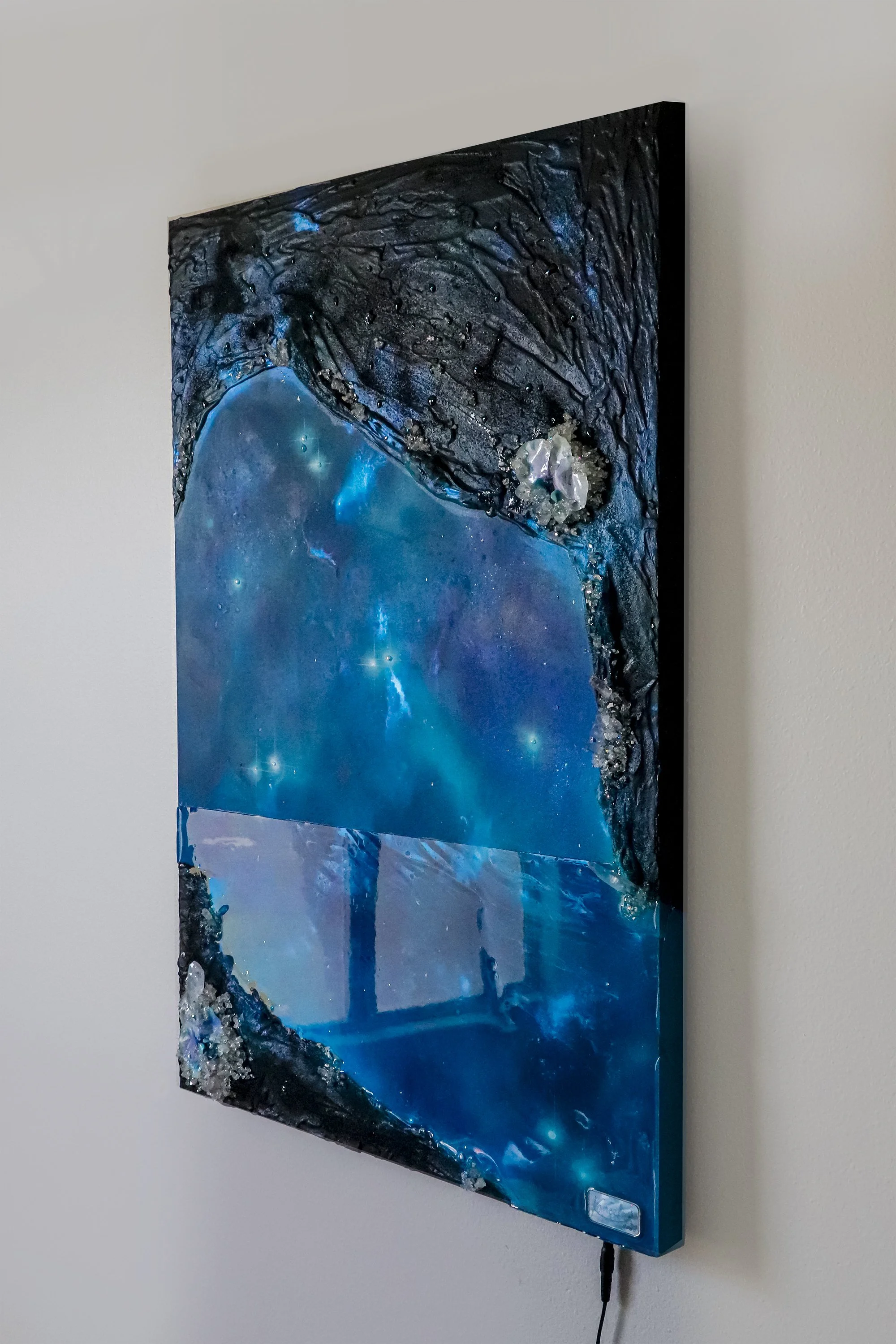 Blue abstract wall art hanging on wall, with orchid botanicals, quartz crystals and resin