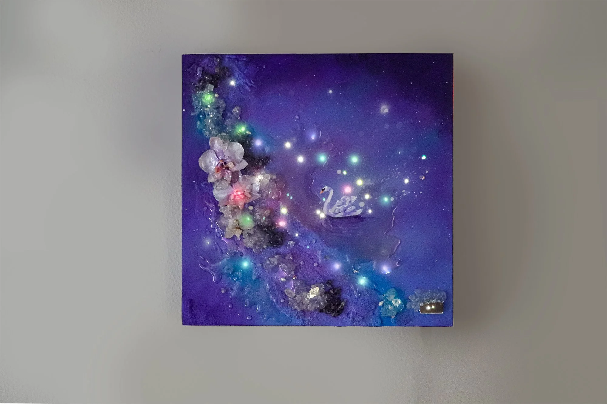 fiber optic wall art hanging on wall, purple pink and blue colors with botanical preserved orchids and quartz crystals, glowing led lighting, swan painting