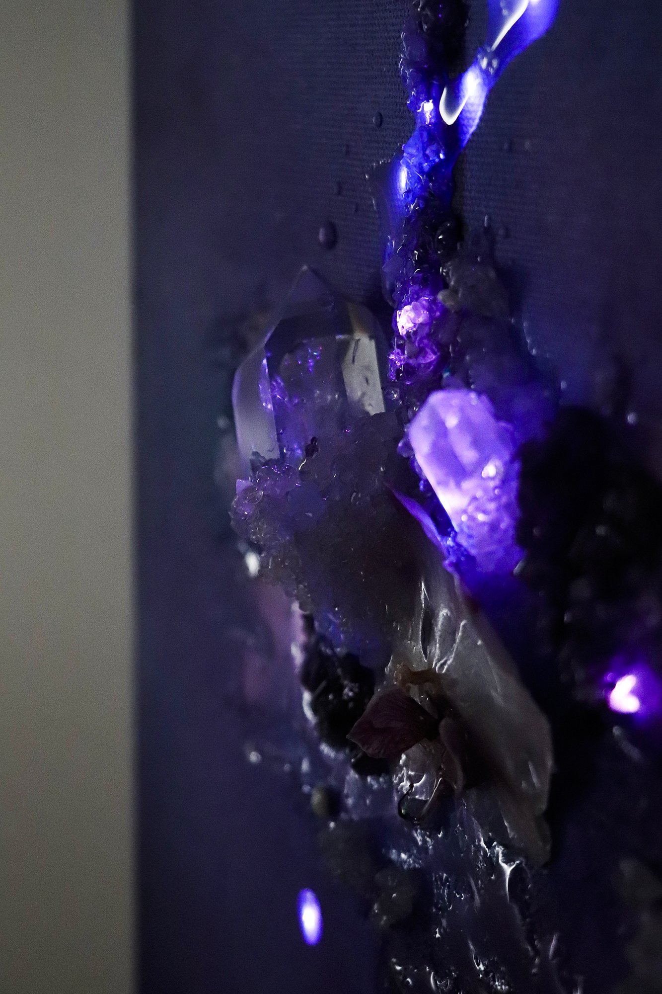close up detail photo of quartz crystal with preserved orchid flower glowing crystal in the dark with purple fiber optic LED lighting