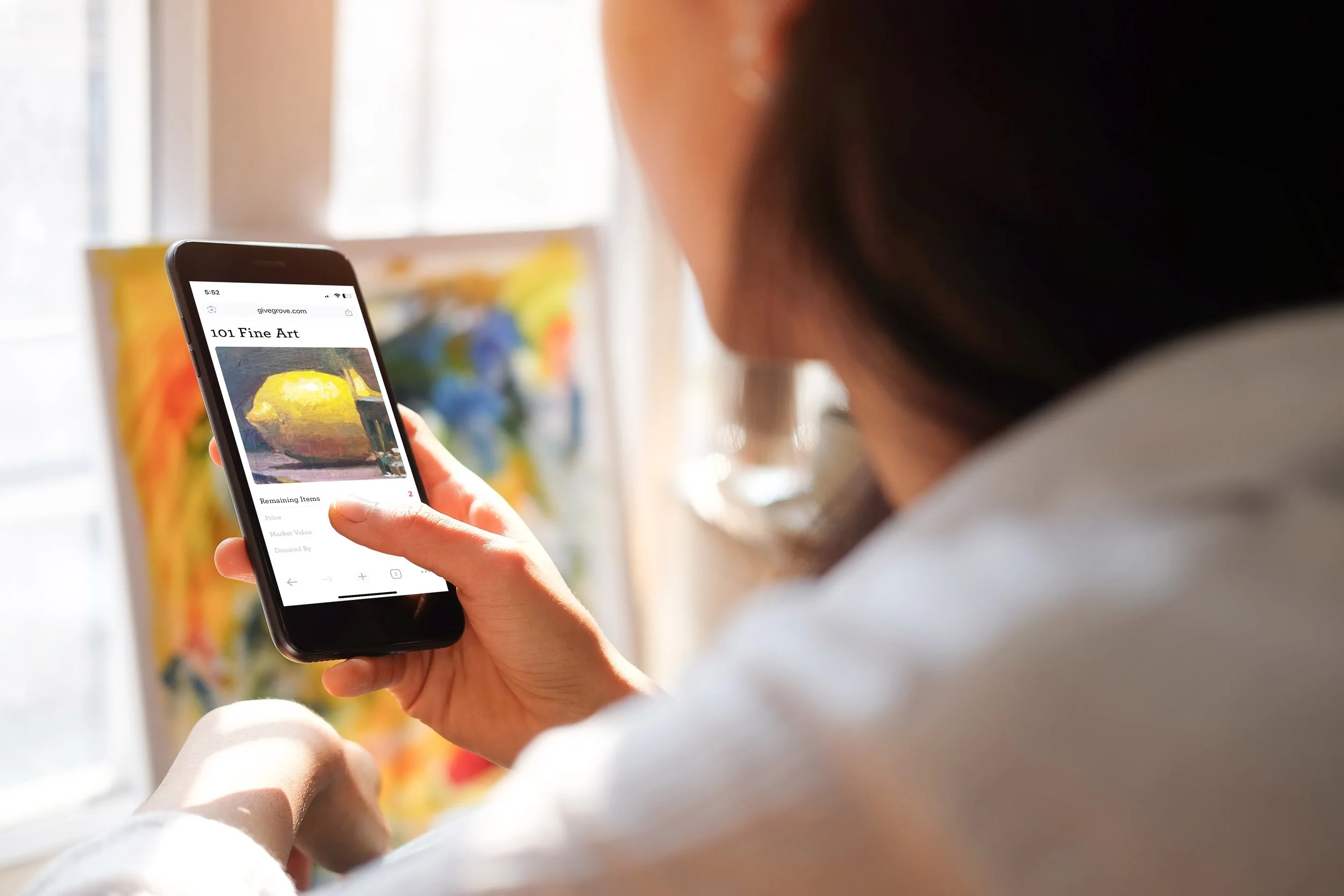 Person viewing an online auction on a smartphone with an art painting on the screen.