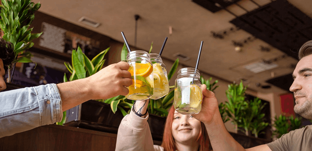 Three people holding glasses filled with citrus drinks together
