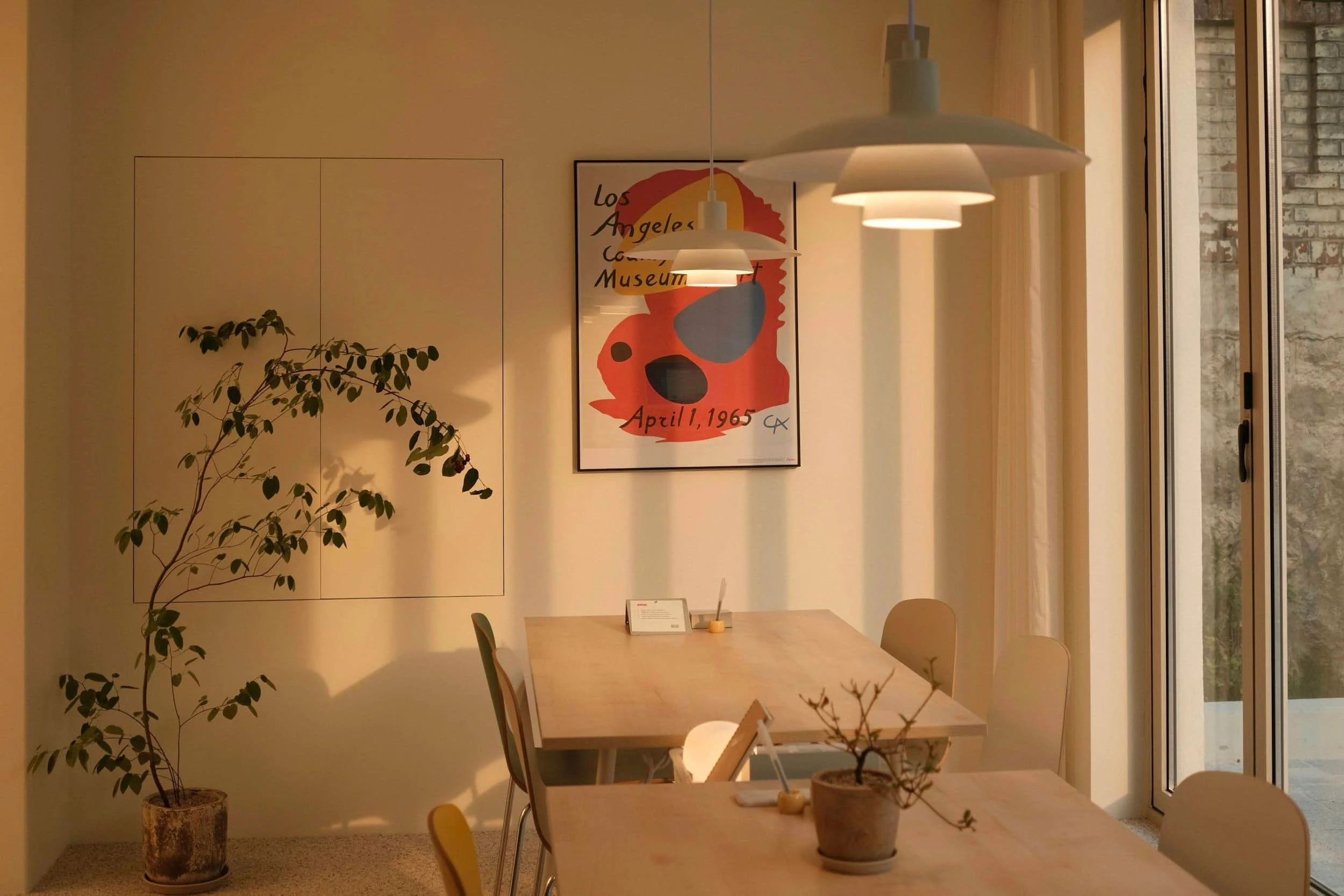 tables with chairs and vintage poster on the wall with a plant next to it