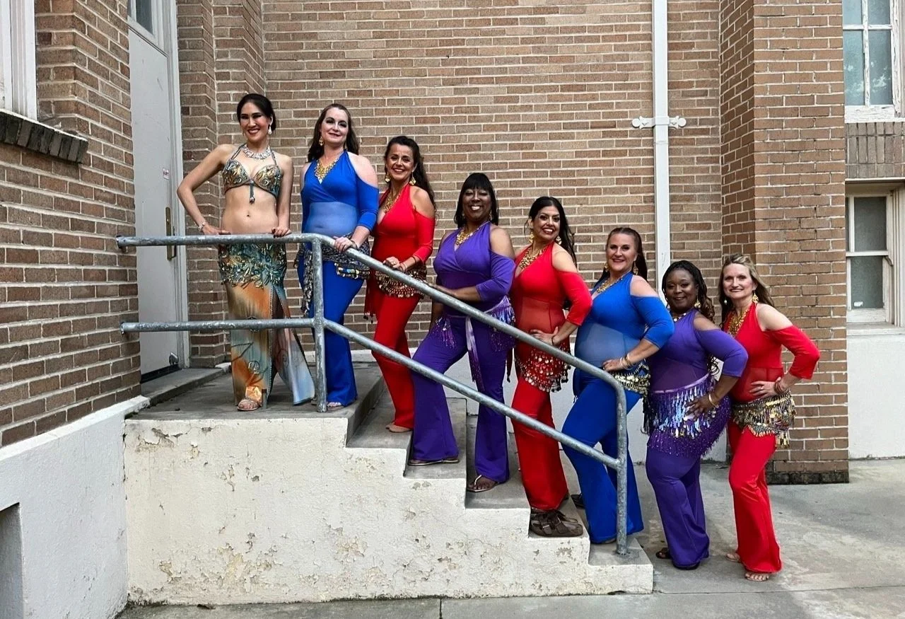 stephaniebellydance.com features Stephanie and her troupe Daira in colorful unitards lining up the stairs leading into Alegria's spring showcase 2024.