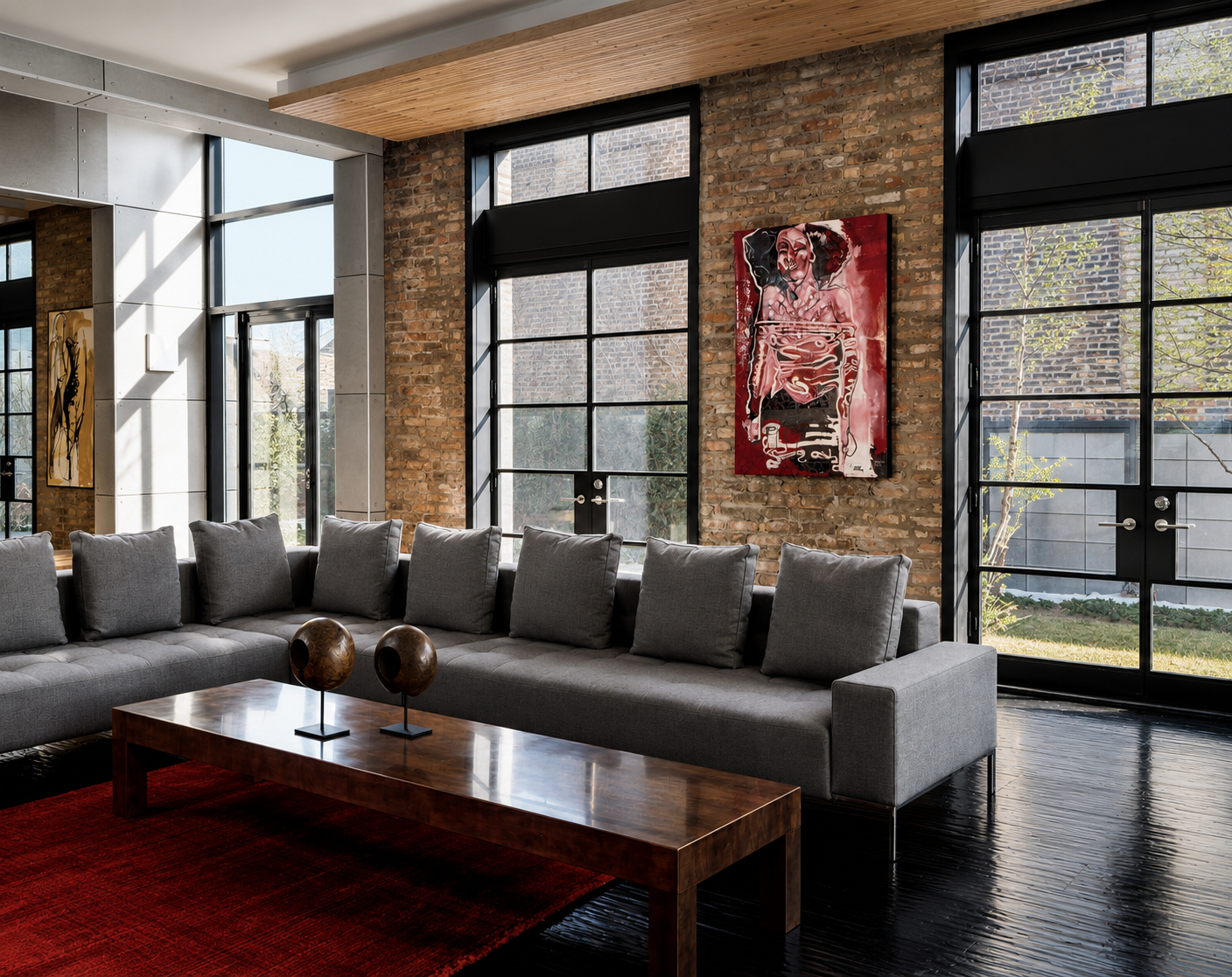 Modern living room with brick and metal wall, large windows, gray sectional sofa, wooden coffee table, and contemporary artwork on the wall.