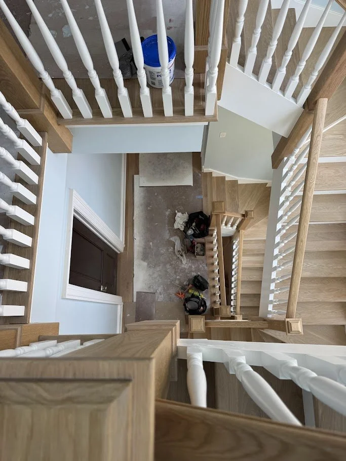 Top-down view of a staircase at a construction site, with tools and construction supplies on the landing area.