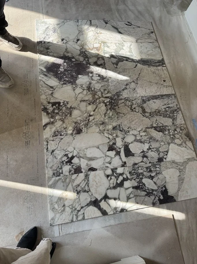 Marble tiles with a black, white, and gray veined pattern on a floor.