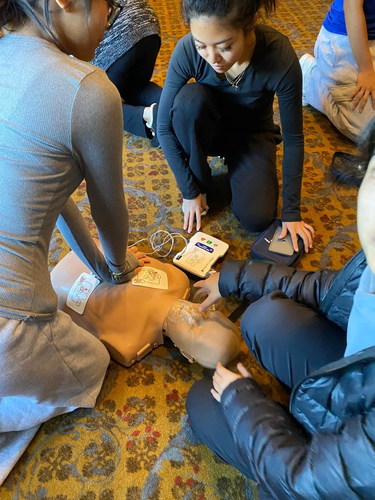 learners practicing CPR on an adult mannequin and suing AED